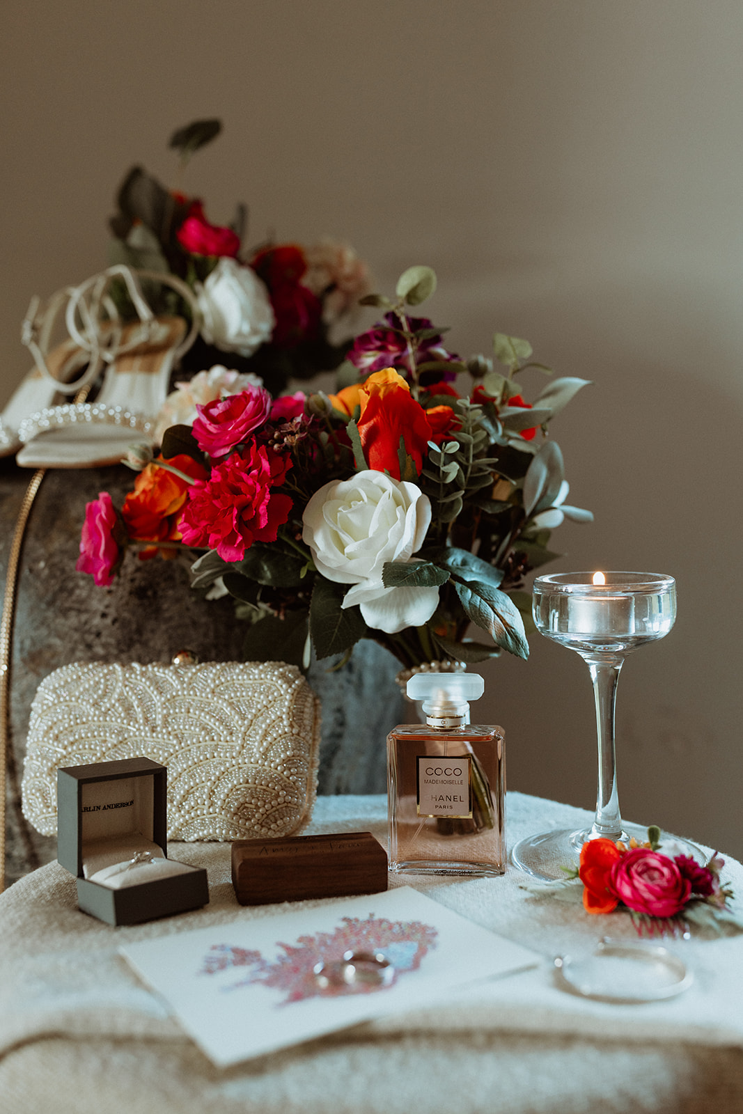 Amy’s elegant bridal shoes resting next to her wedding rings, made by Amy Paul Jewellery, surrounded by colourful flowers at Eirð Retreat.