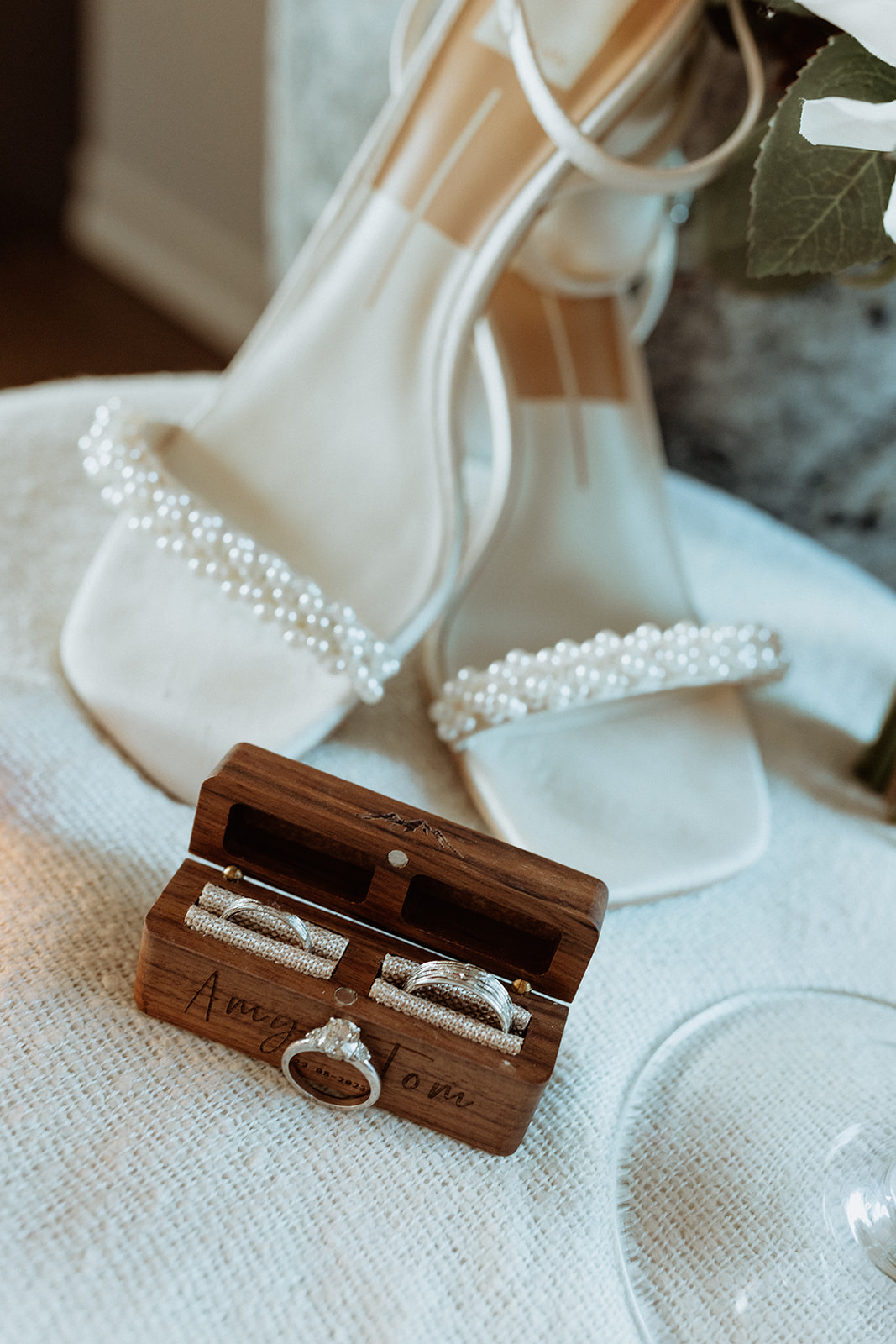 Amy’s custom wedding band and engagement ring from Amy Paul Jewellery, gently resting on a rustic surface with Icelandic wildflowers at Eirð Retreat.
