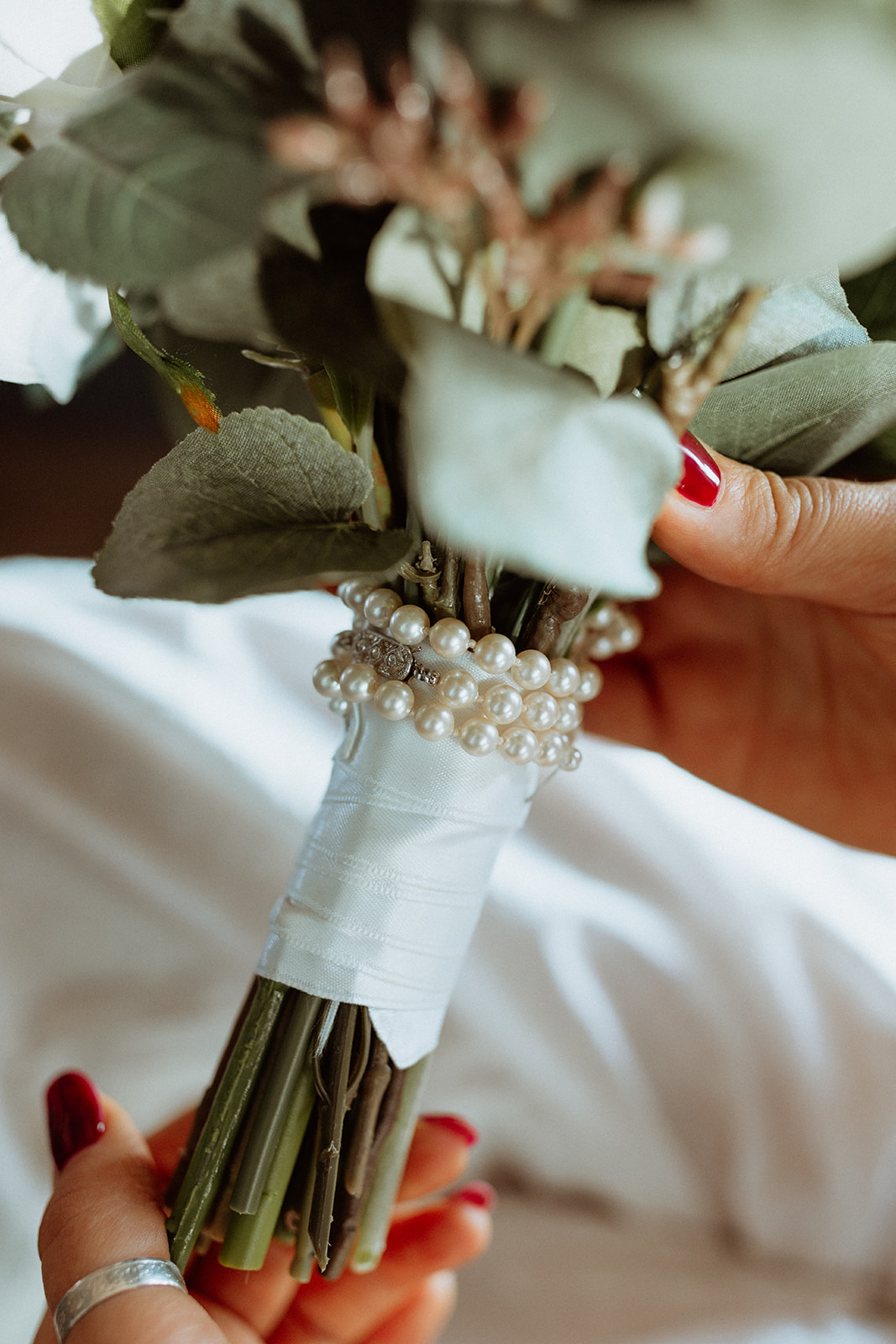Close-up of a bridal bouquet with pearls delicately woven into the flowers, showcasing elegant wedding details.