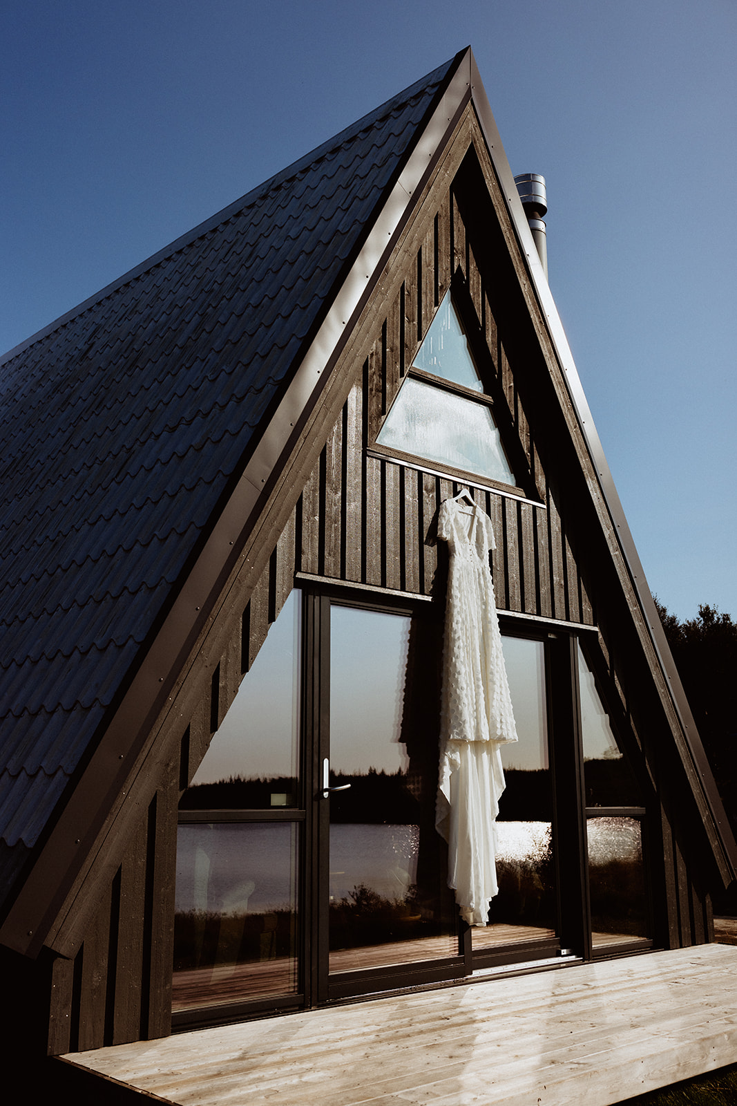 Amy’s bridal gown elegantly hanging from the A-frame at Eirð Retreat, capturing the beauty of the dress against Iceland’s tranquil scenery