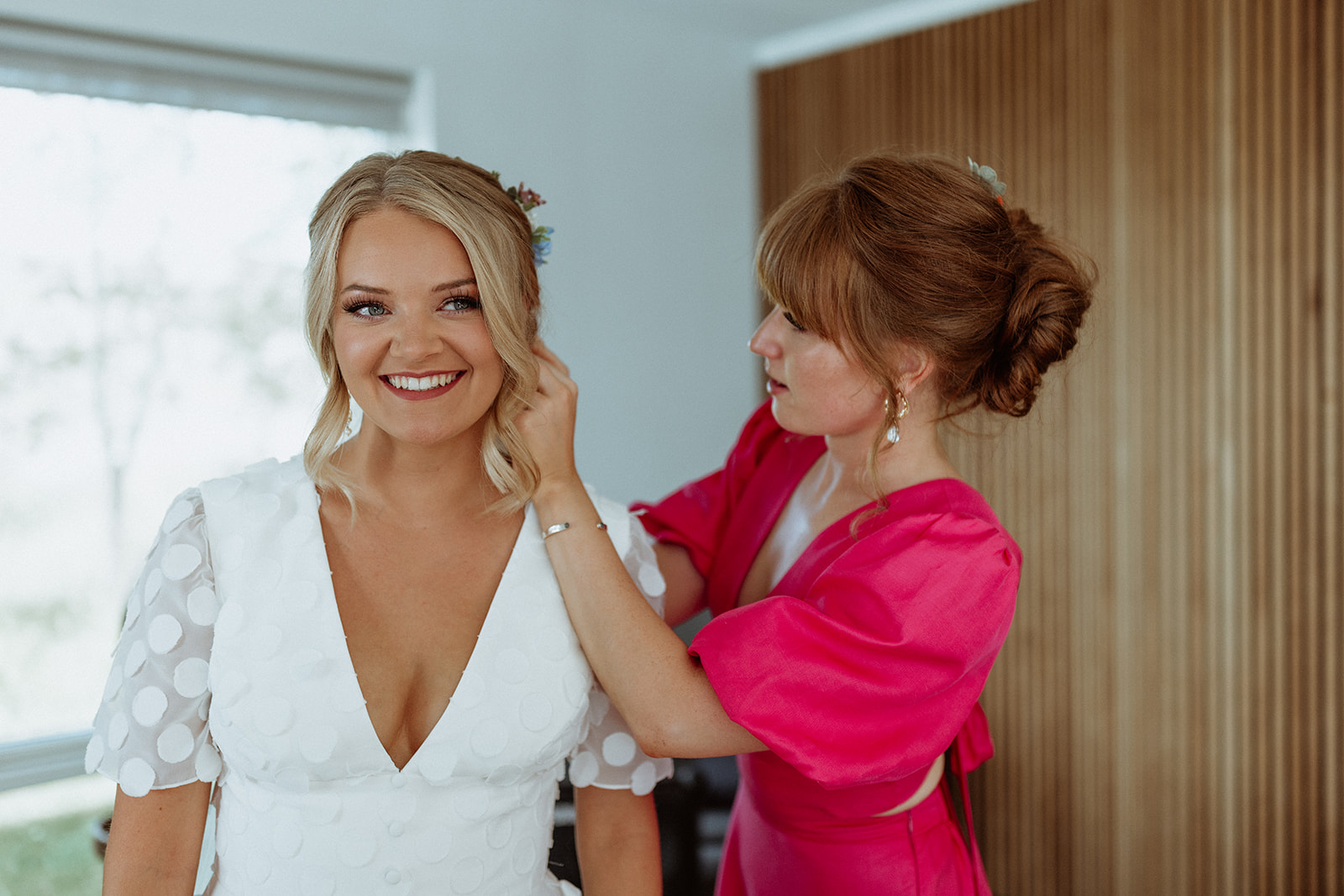 Bridesmaid helping the bride put in her earring, an intimate moment captured during their Icelandic elopement preparations.