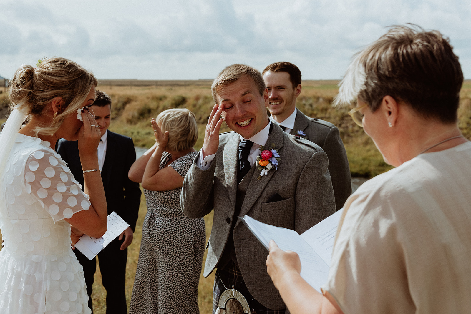 Tearful groom wiping away a tear during the emotional exchange of vows at their Icelandic elopement at Gluggafoss waterfall.