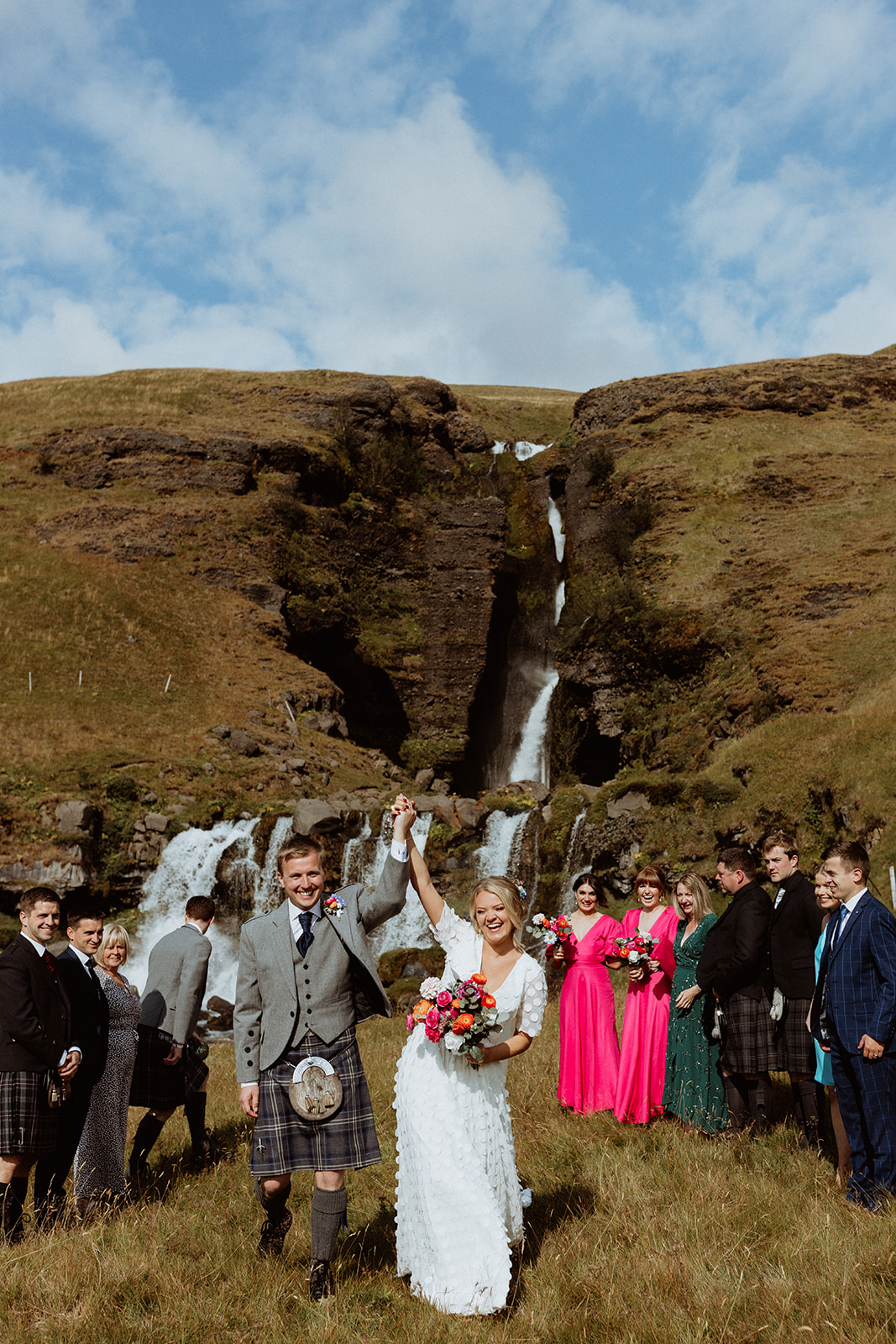 Bride and groom celebrating their elopement in Iceland with cheers and a kiss in front of Gluggafoss waterfall