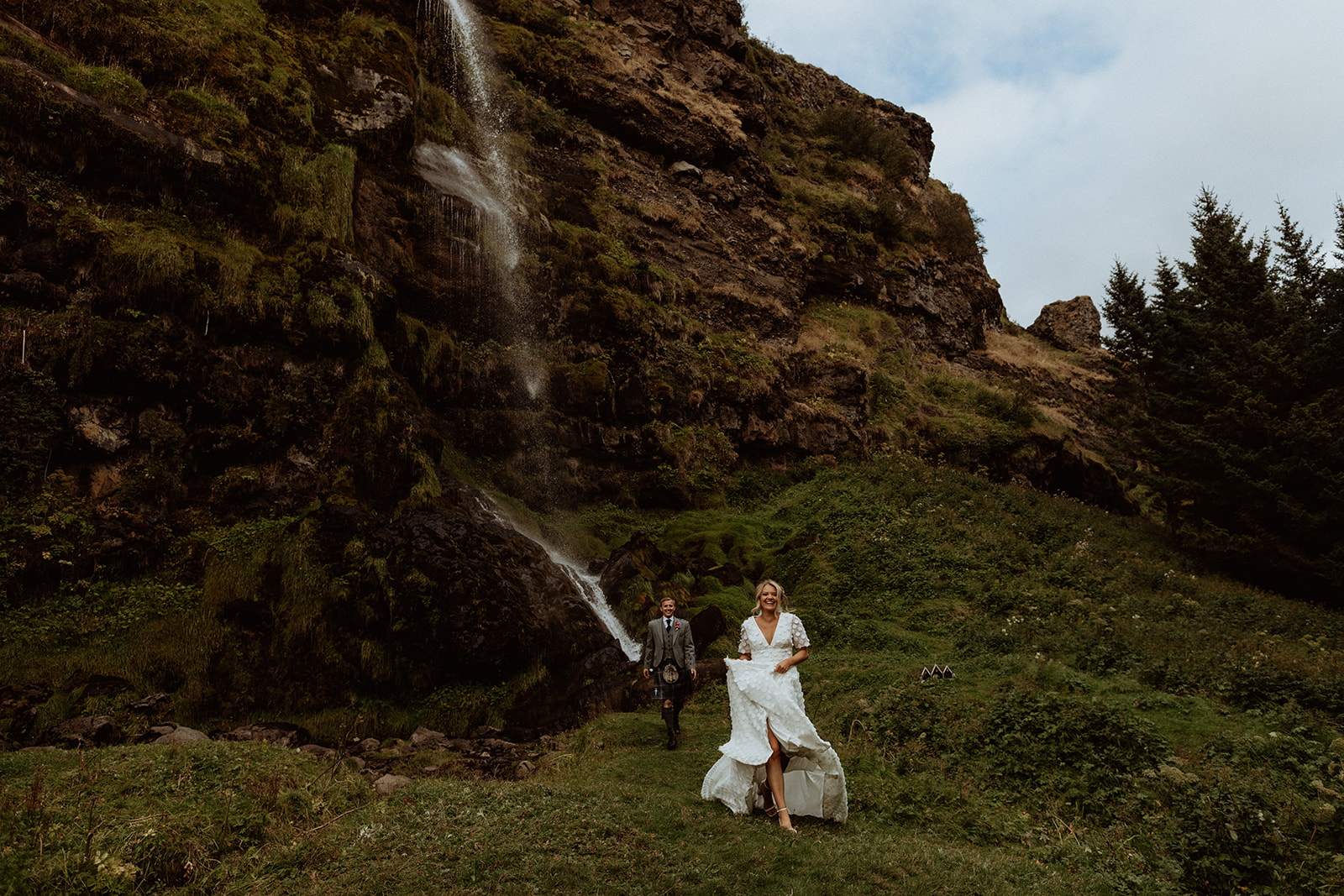 Newlywed couple enjoying a private moment beneath the serene Þorsteinn's waterfall during their Iceland elopement.
