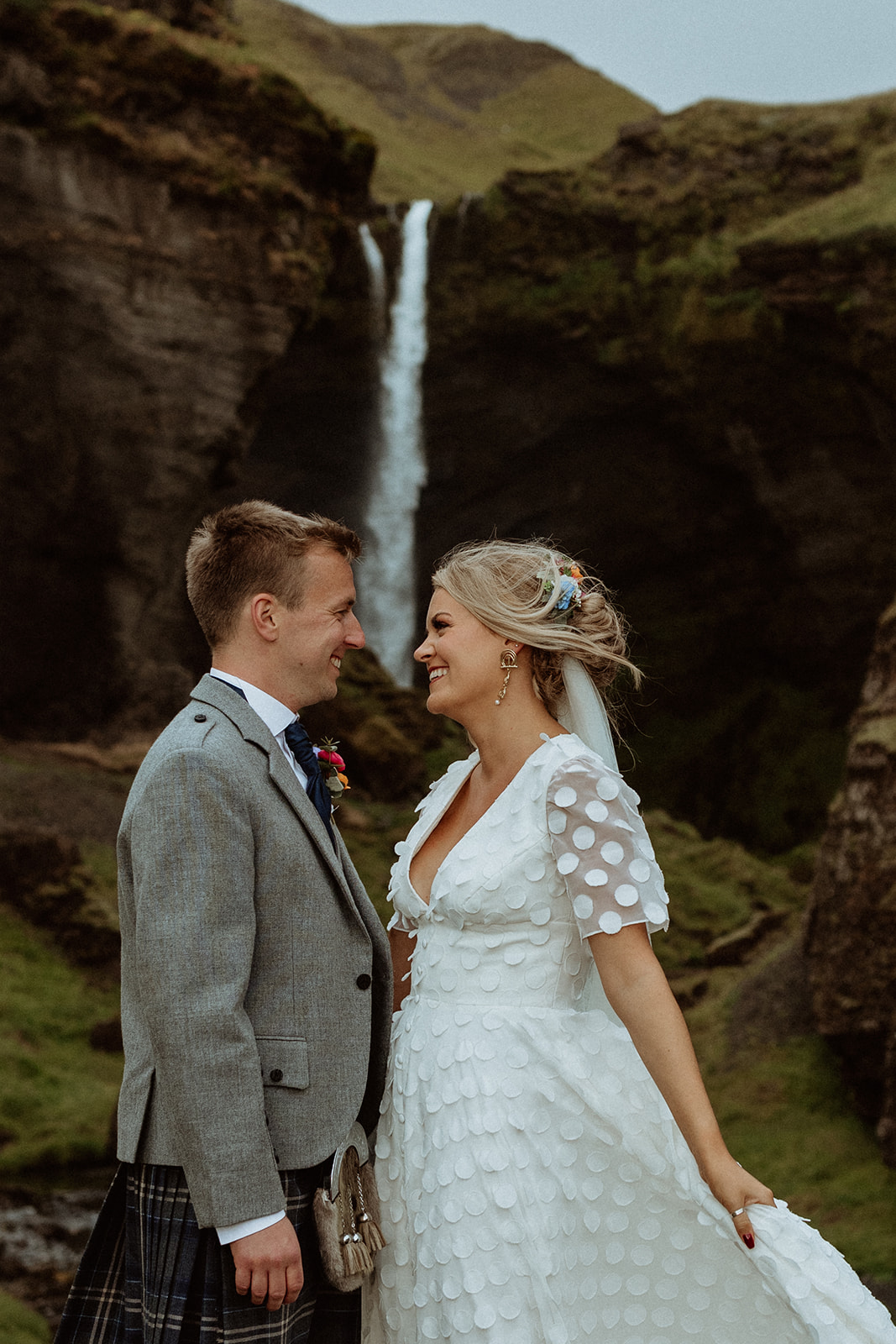 Newlyweds standing together in front of Kvernufoss waterfall, embracing the beauty of Iceland during their intimate elopement.