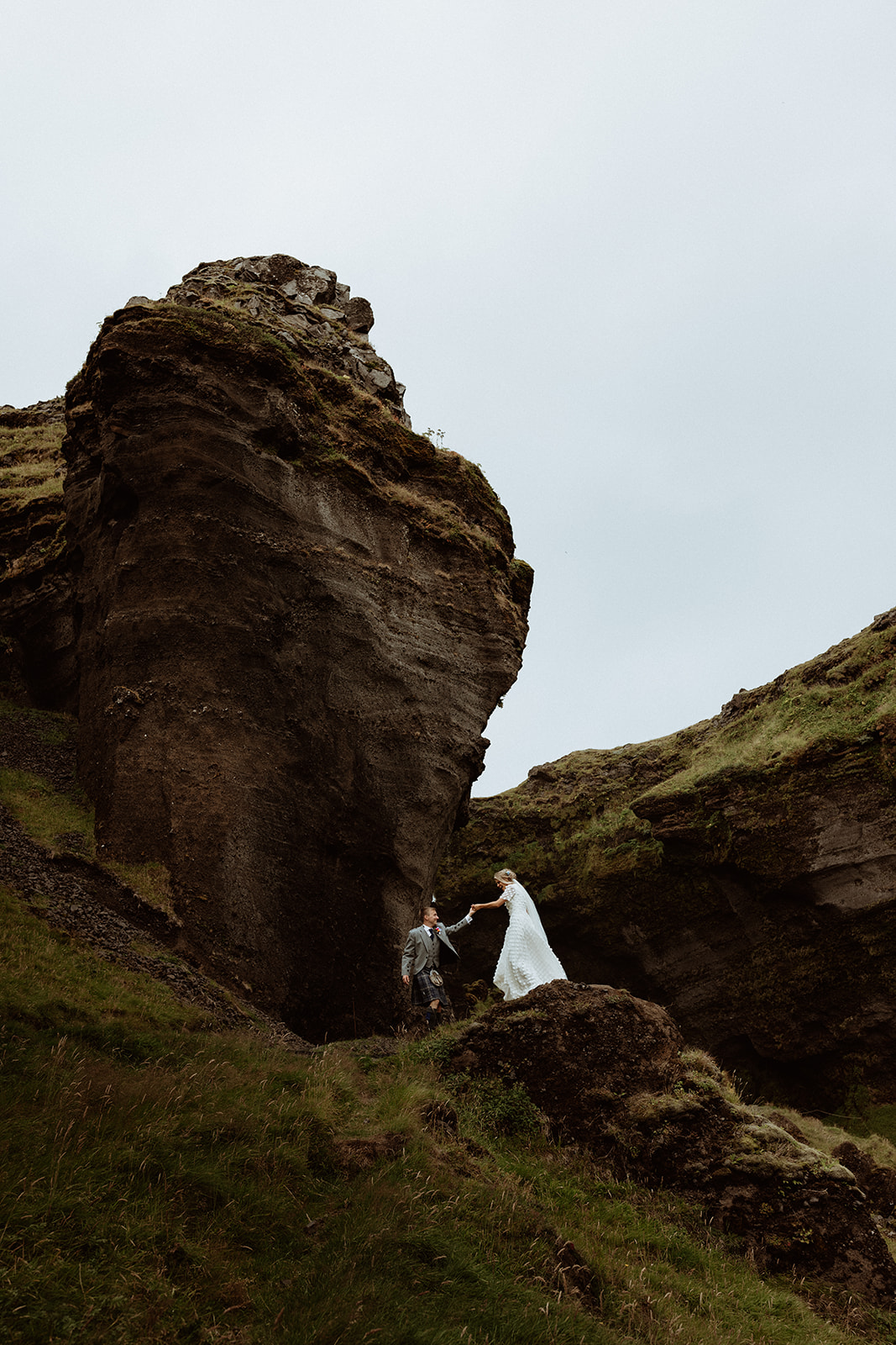 Bride and groom walking hand-in-hand near the misty Kvernufoss waterfall, surrounded by Iceland’s stunning landscape." Title: "Bride and Groom Walking Near Kvernufoss Waterfall, Iceland