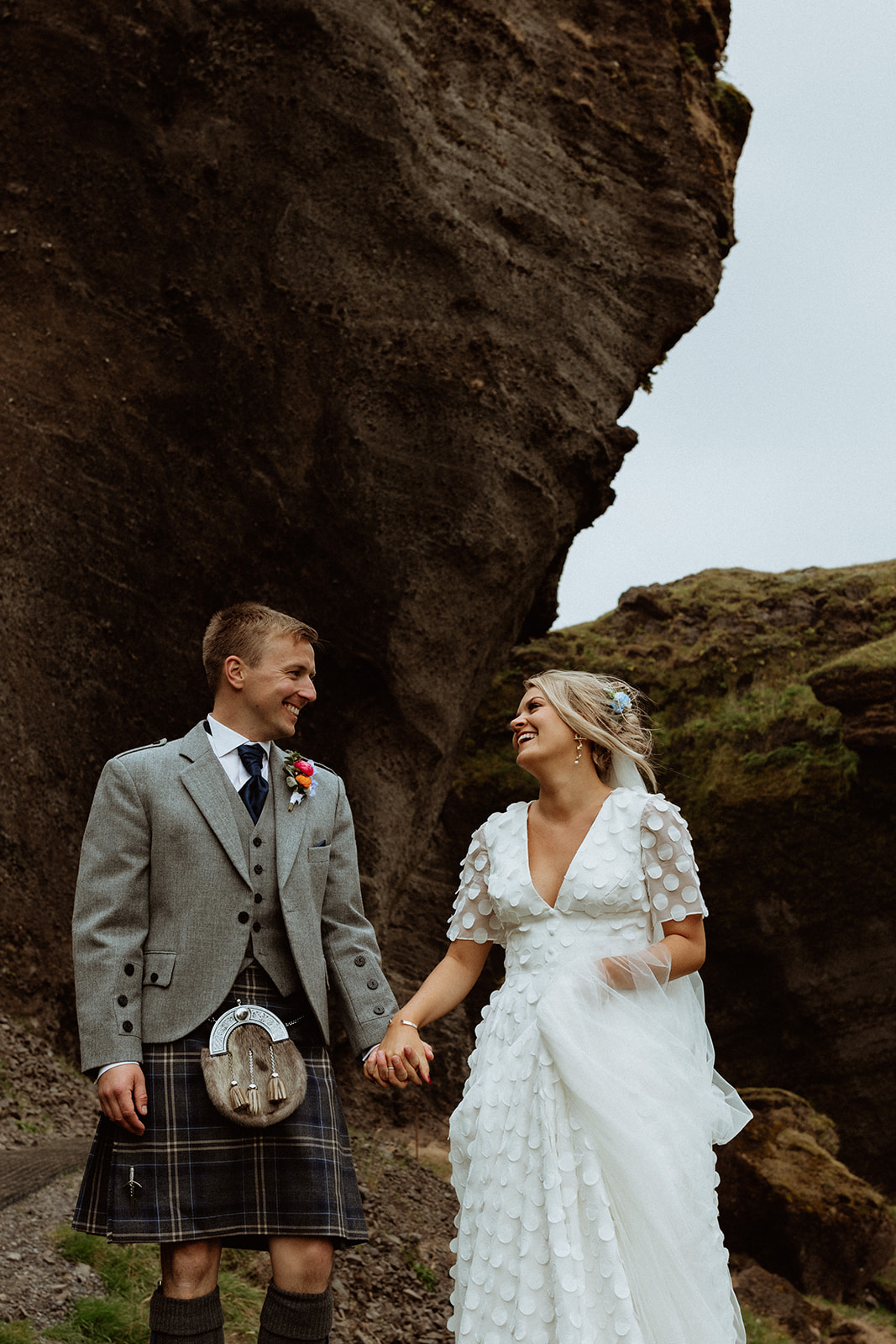 The bride and groom standing together at the base of Kvernufoss waterfall, sharing a peaceful moment after their elopement