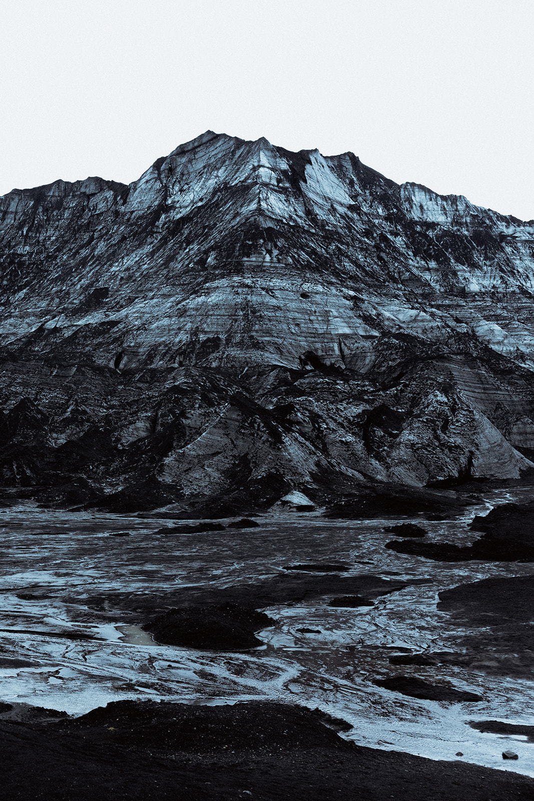 Black volcanic rock and pristine snow contrast on the surface of Katla ice cave, showcasing Iceland’s unique landscape.