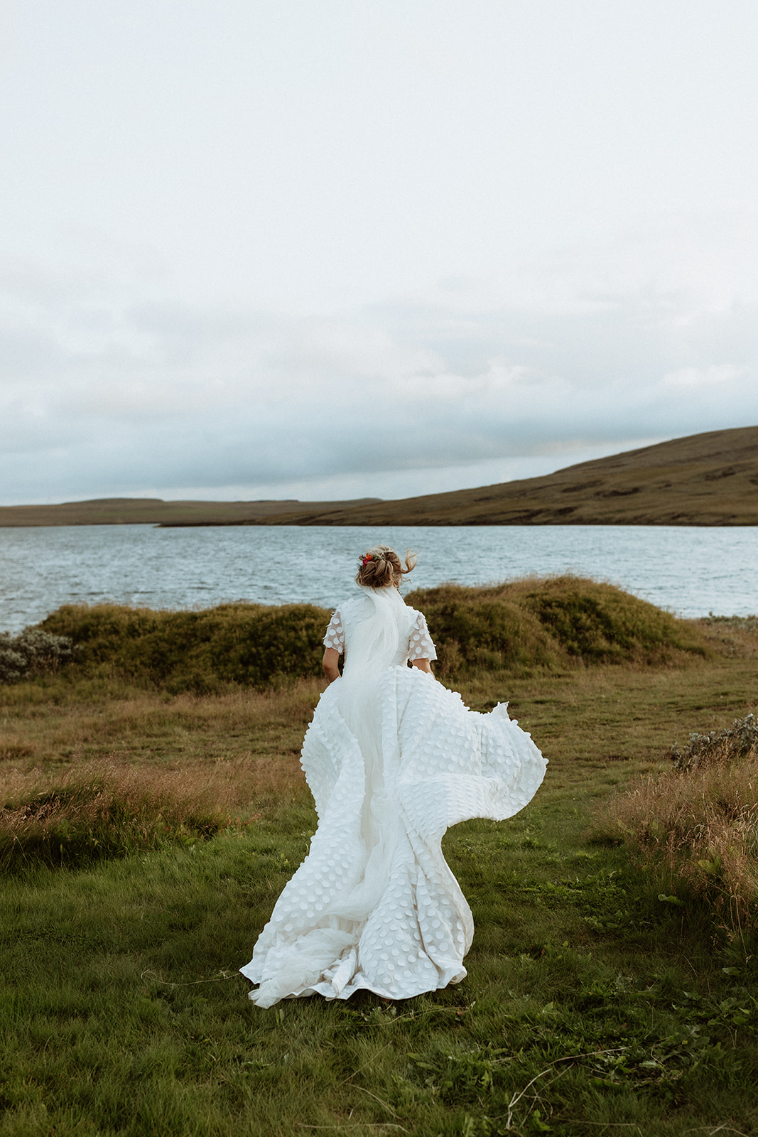 Bride running across the rugged Icelandic terrain, her veil trailing behind her, capturing a moment of pure joy and spontaneity during her adventure elopement.
