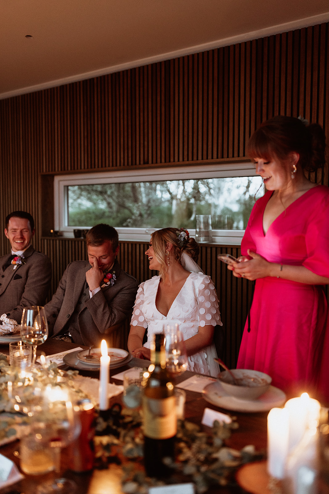 Bridesmaid delivering a speech at the Icelandic elopement celebration, with guests laughing and enjoying the heartfelt moment."