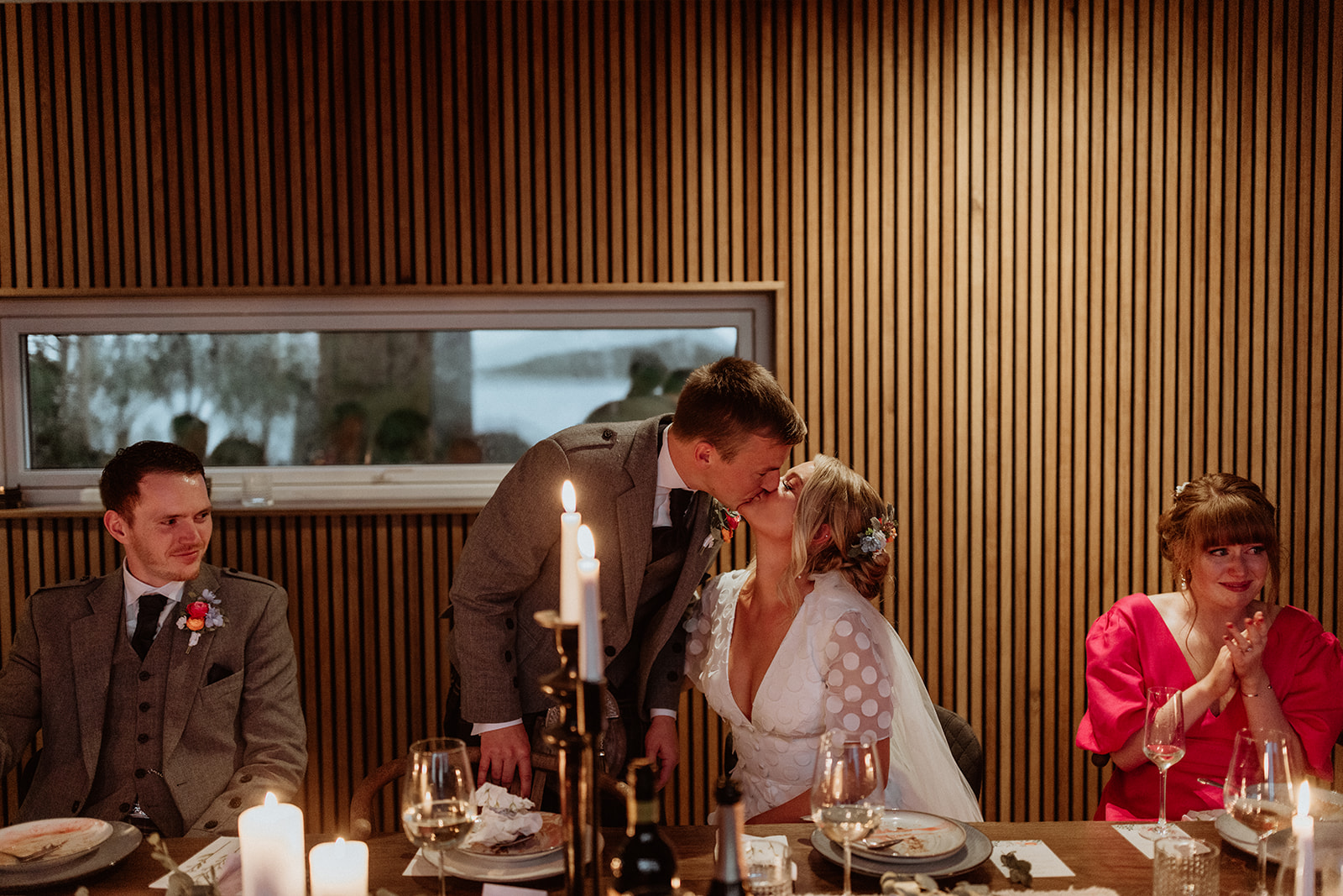 The bride and groom share a kiss after an emotional speech, surrounded by their guests during their Iceland elopement celebration.