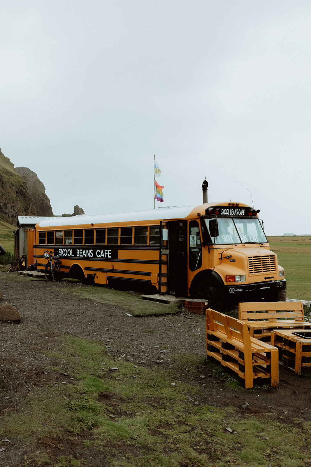 The quirky Skool Beans coffee shop, a converted school bus, serves up warm drinks to the adventurous couple as they embrace Iceland’s wild charm.