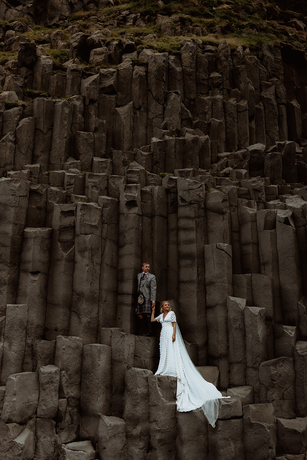 Amy and Tom stand together amidst the towering basalt columns of Reynisfjara Beach, taking in the raw beauty of Iceland’s rugged coastline.