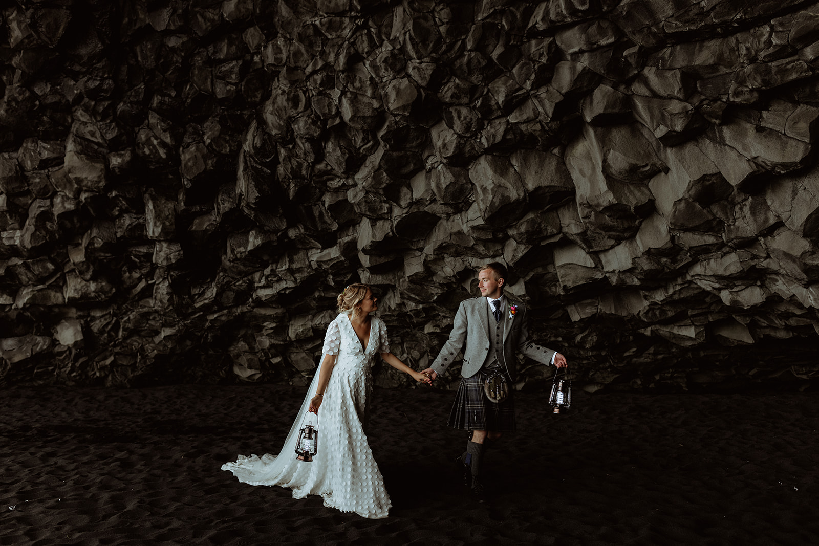 The newlyweds embrace inside the cave at Reynisfjara, Iceland, with the unique rock formations creating a striking, otherworldly atmosphere.