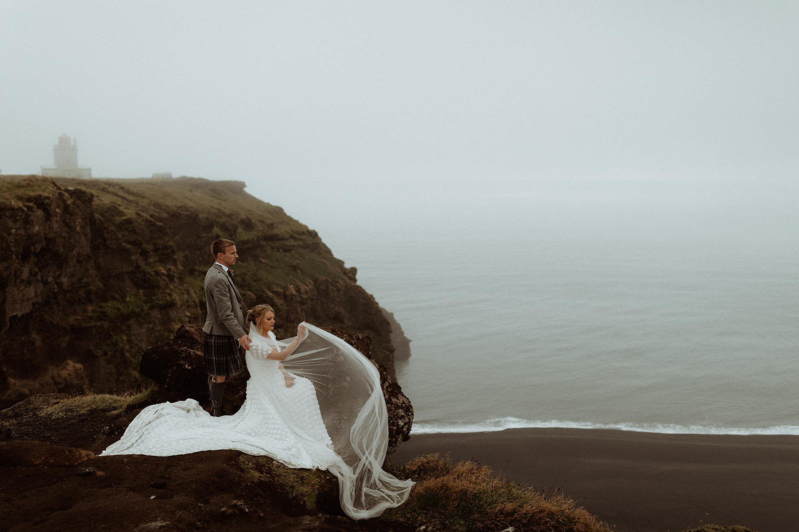 The newlyweds gaze out over Iceland's dramatic landscapes, taking in the stunning beauty of the natural surroundings.
