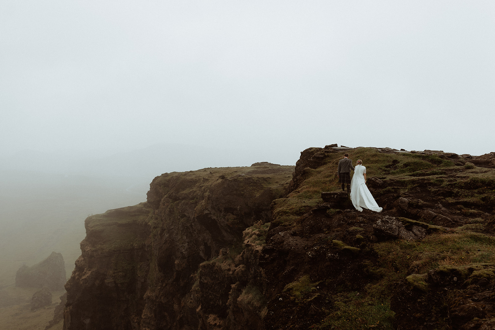 Newlyweds take in the breathtaking scenery from Dyrhólaey, the vast coastline and sea stretching endlessly before them.