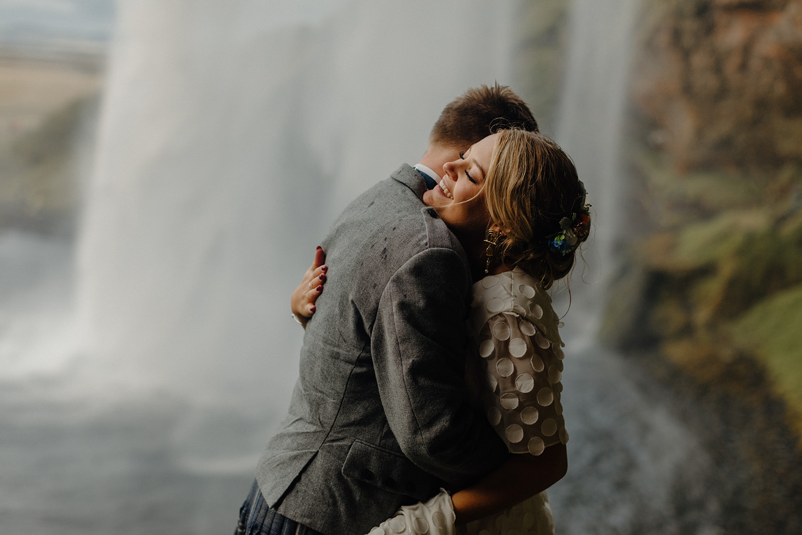 Bride and groom share an intimate moment dancing under the cascading water of Seljalandsfoss waterfall.
