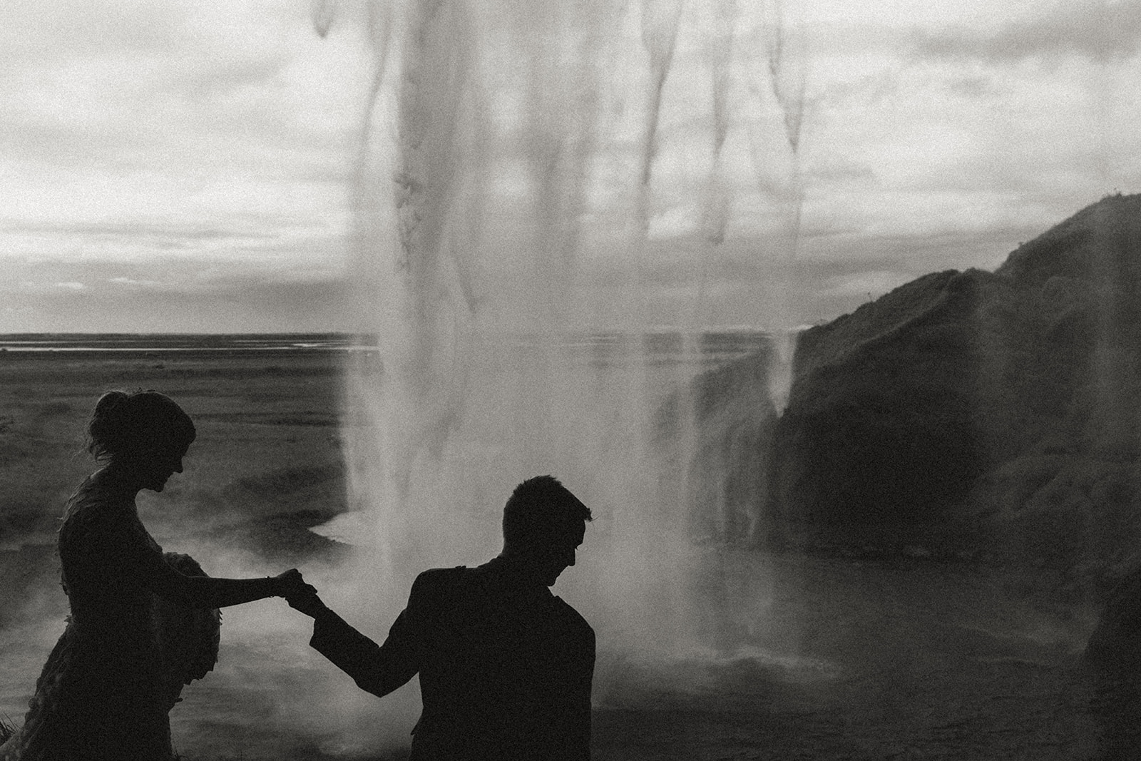Couple dancing joyfully beneath the powerful waterfall of Seljalandsfoss during their Icelandic elopement.