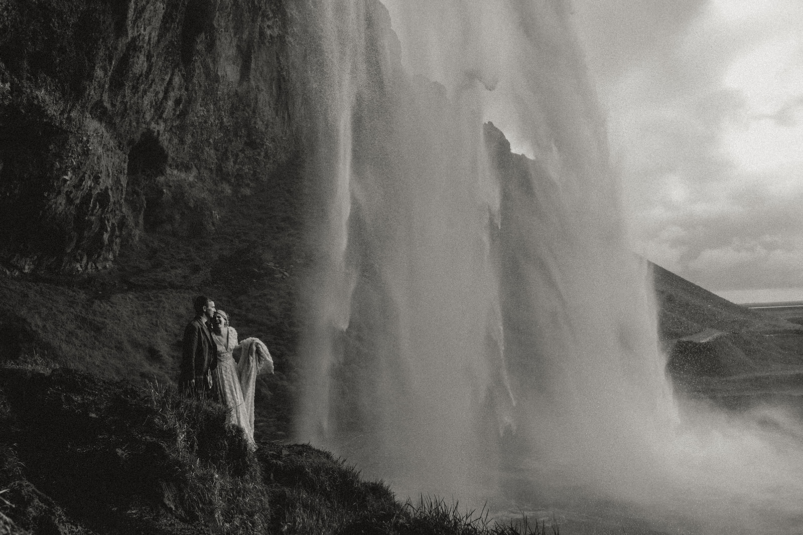 Newlyweds spinning in each other's arms near the iconic Seljalandsfoss waterfall during their Icelandic adventure elopement.