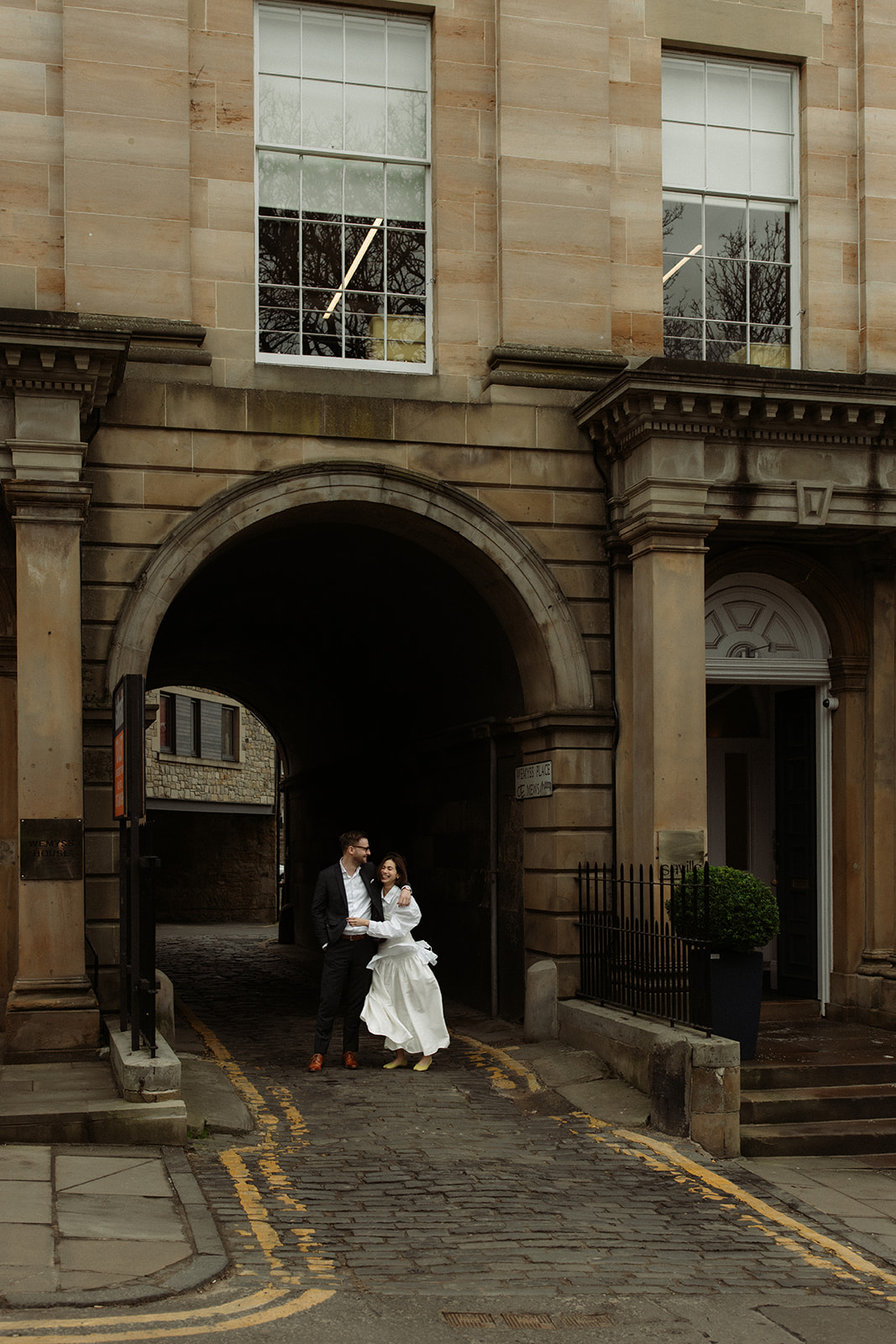 Editorial engagement photo in Edinburgh with a couple walking hand-in-hand through charming city streets