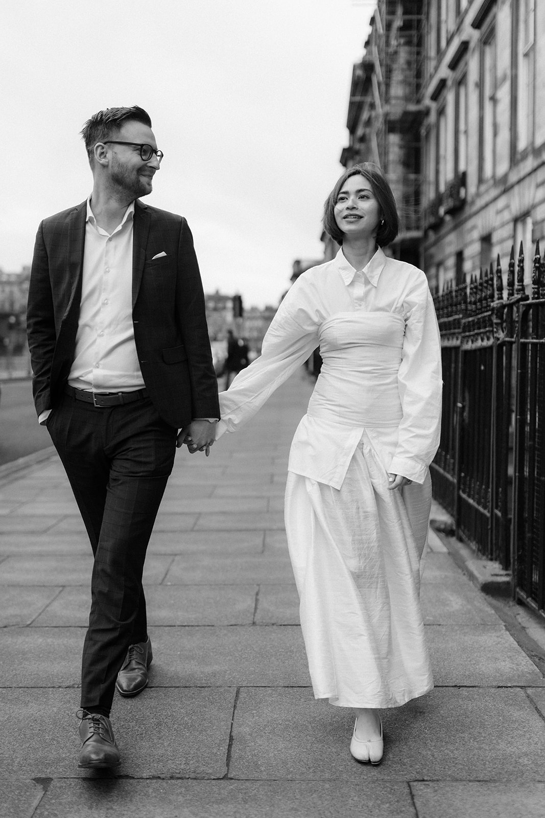 Couple strolling hand-in-hand through Edinburgh's picturesque streets during an engagement session.