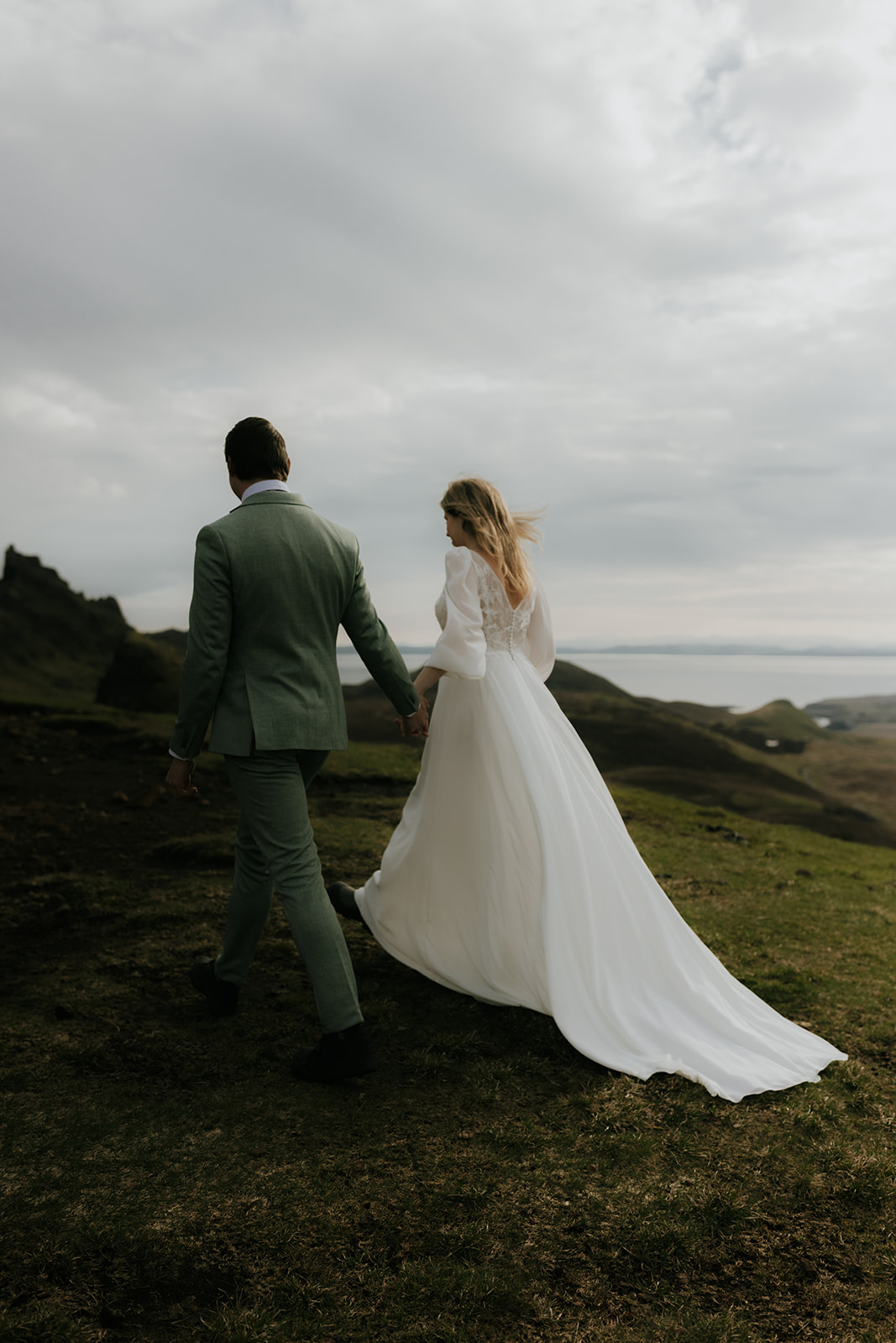 Couple walking hand in hand through the dramatic Isle of Skye landscape