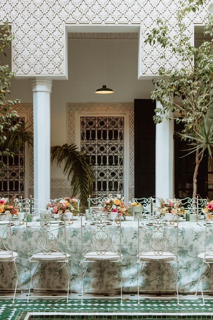 Elegant wedding table set for guests in a Marrakesh riad courtyard.