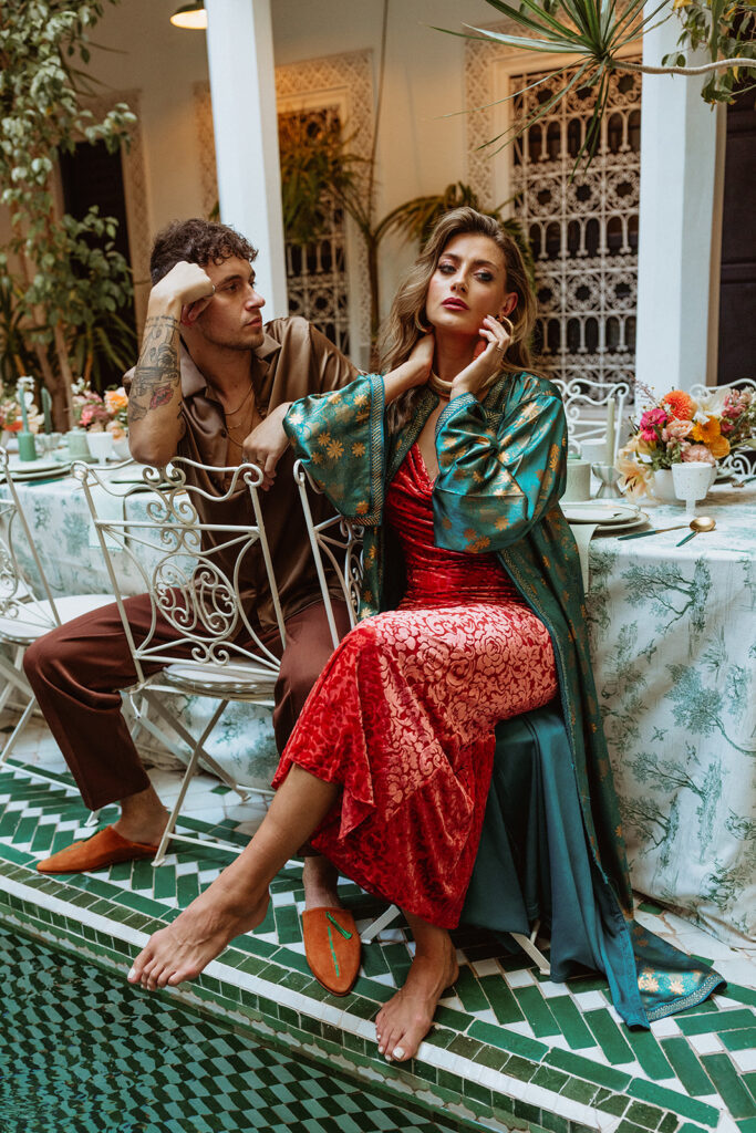 Couple seated at an elegant table in Marrakesh courtyard, editorial pose
