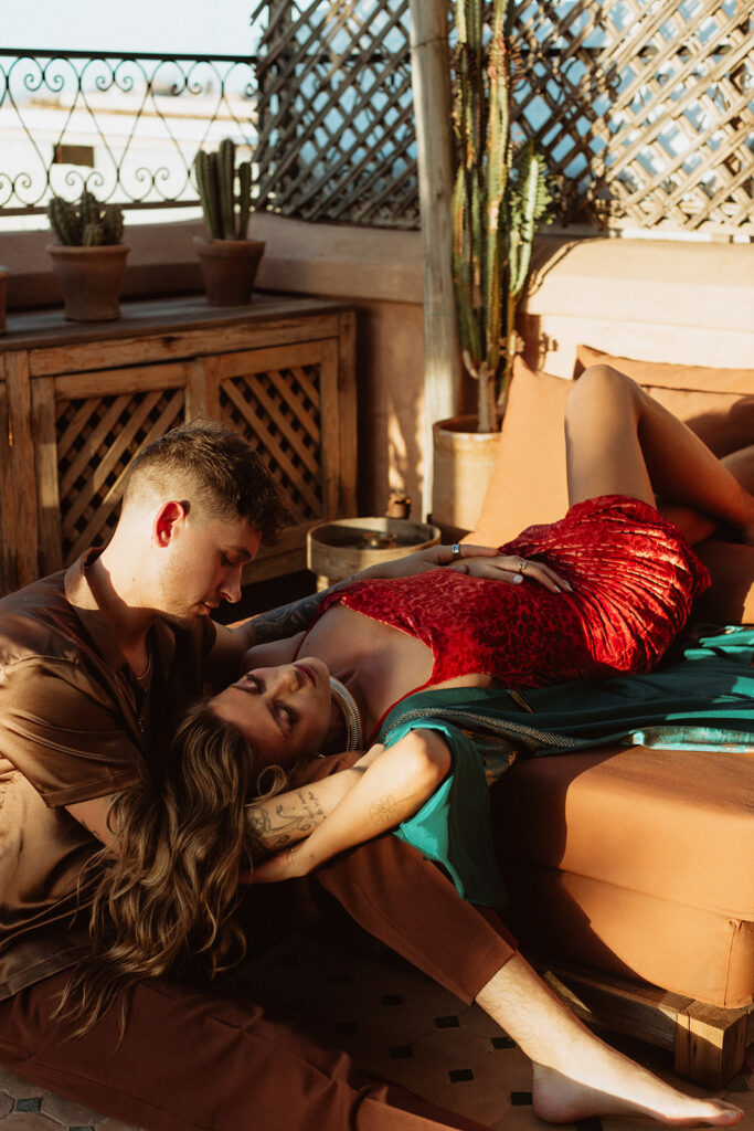 Bride in red gown seated on a rooftop with groom in Marrakesh