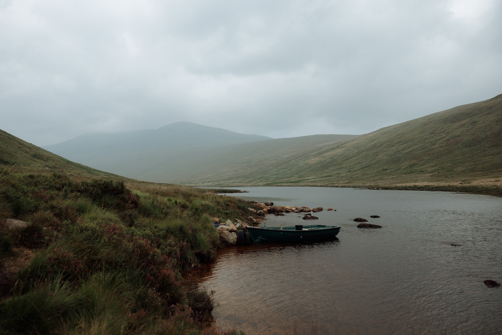 Boat moored on Loch Iorsa with misty hills in the background, Isle of Arran.