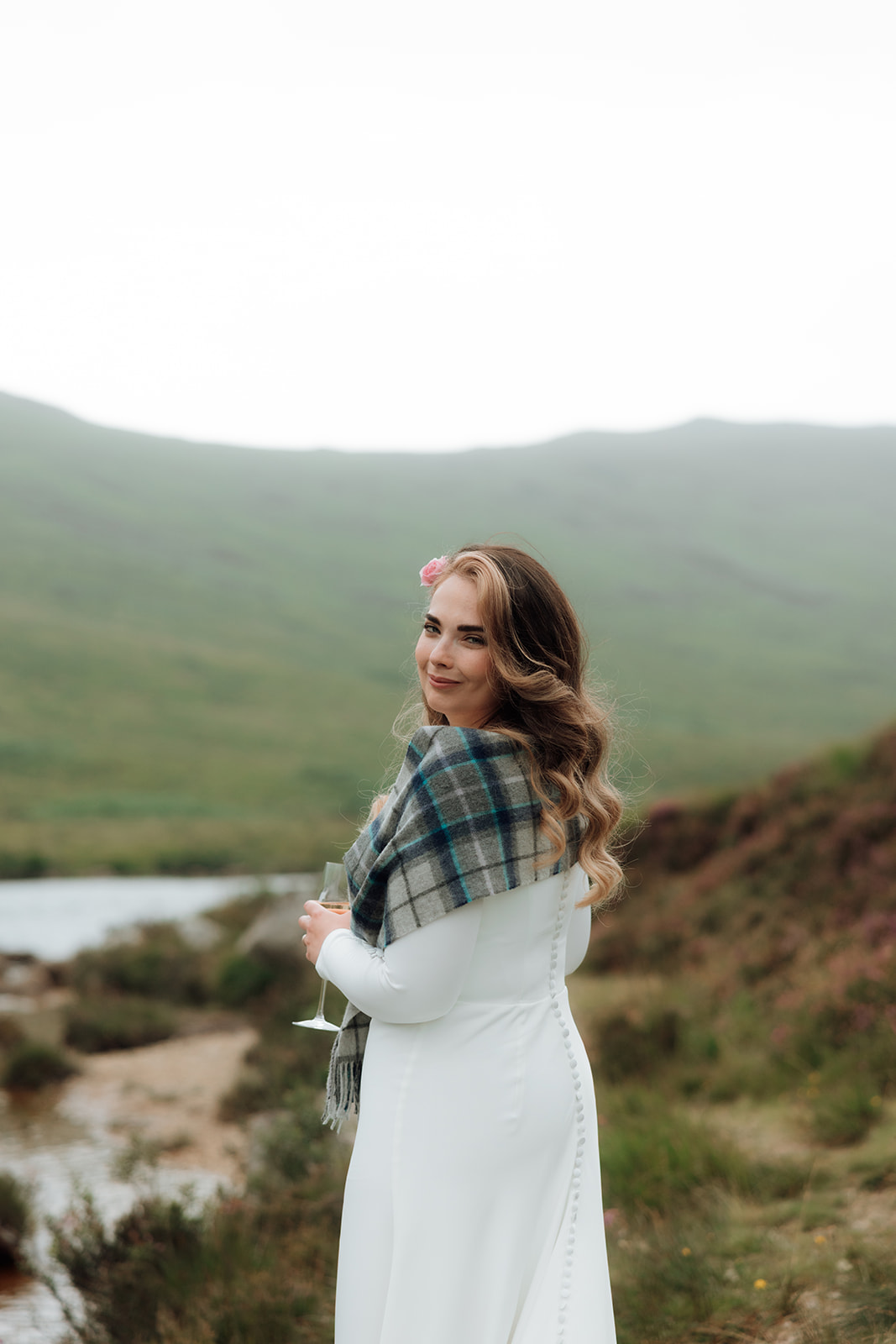 Bride looking back over her shoulder with loch behind during Isle of Arran elopement.