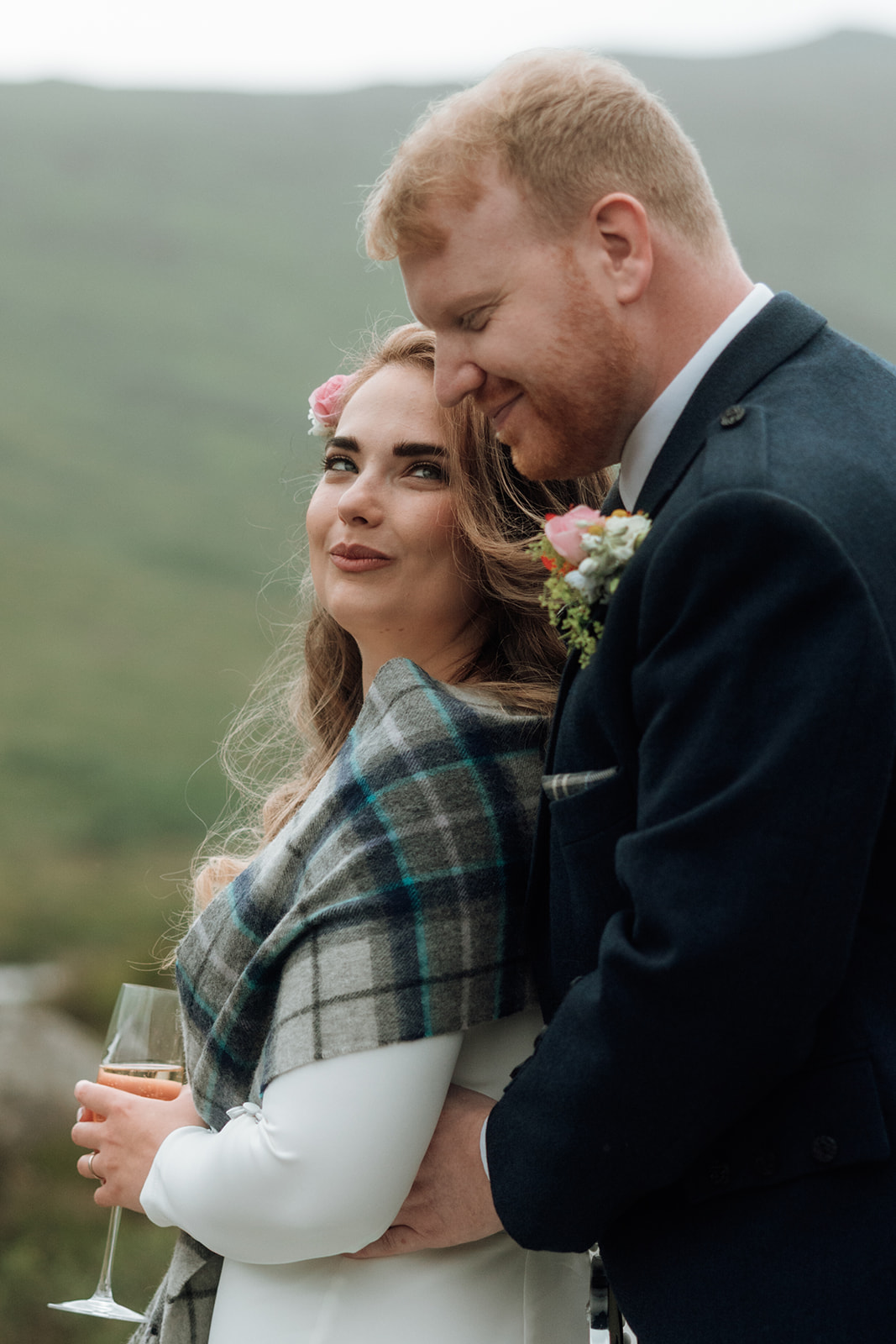 Bride wearing tartan shawl with groom beside her at Isle of Arran elopement.