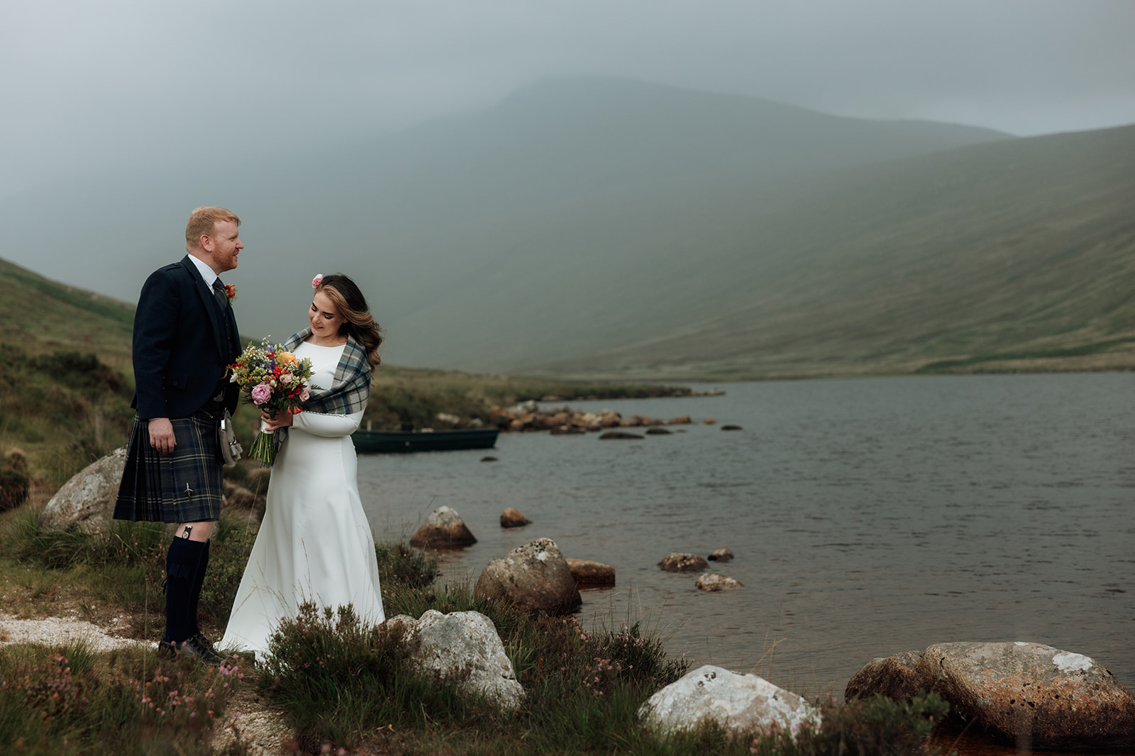 Bride and groom facing each other beside Loch Iorsa during Isle of Arran elopement.