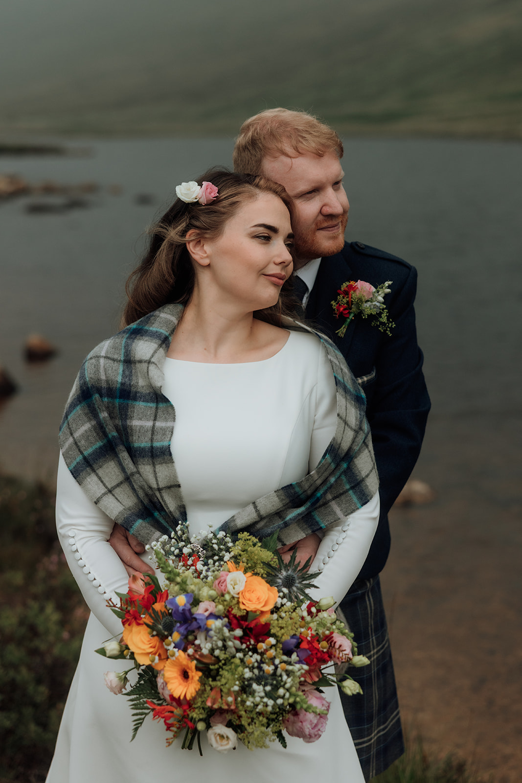 Bride holding bouquet smiling at groom during Isle of Arran elopement.