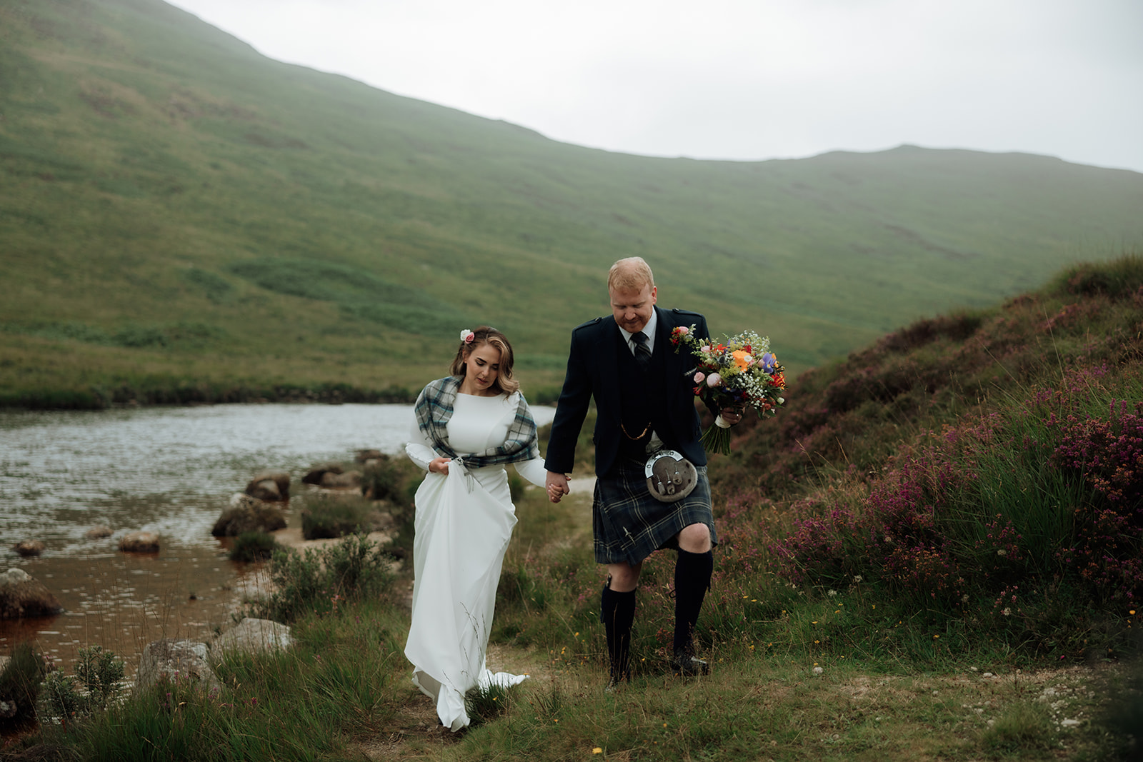 Bride and groom walking hand in hand by the loch during Isle of Arran elopement.