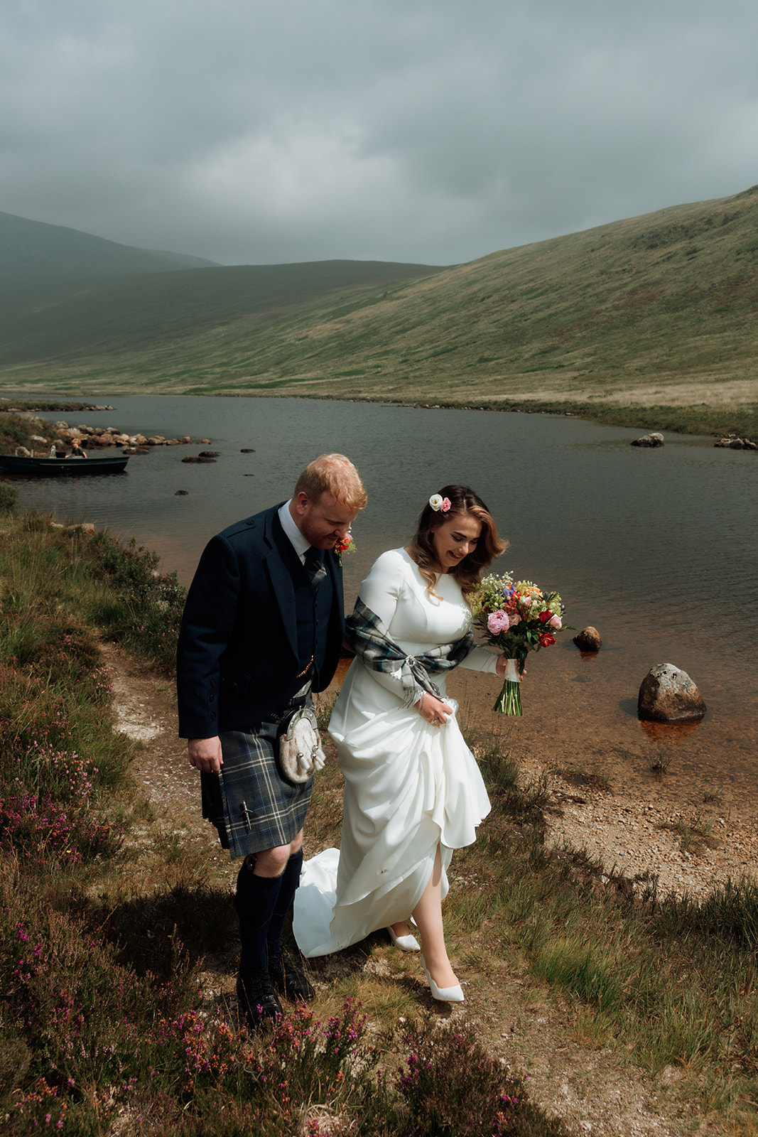 Bride and groom walking together along the loch shore on the Isle of Arran.