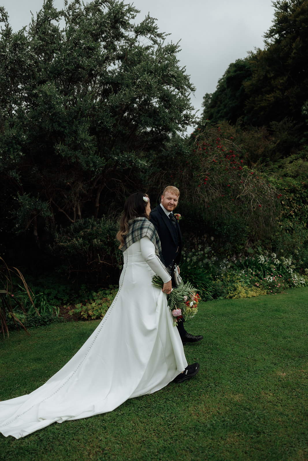 Bride and groom walking through garden during Isle of Arran elopement.