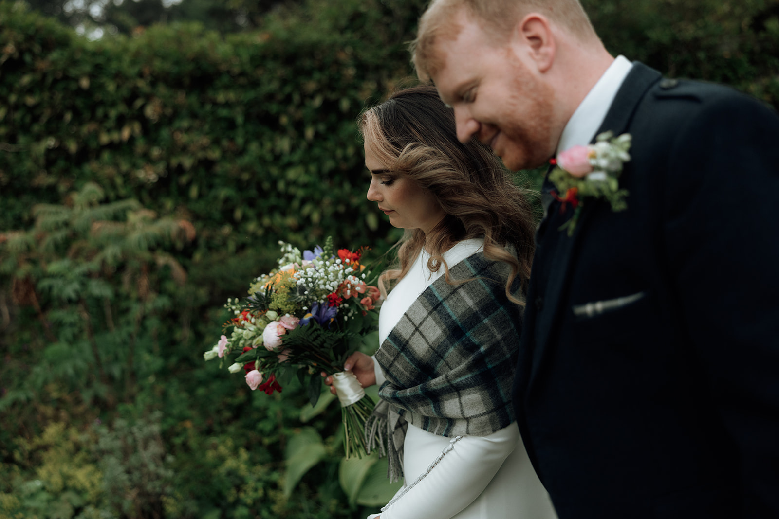 Bride holding colourful bouquet with groom beside her during Isle of Arran elopement.