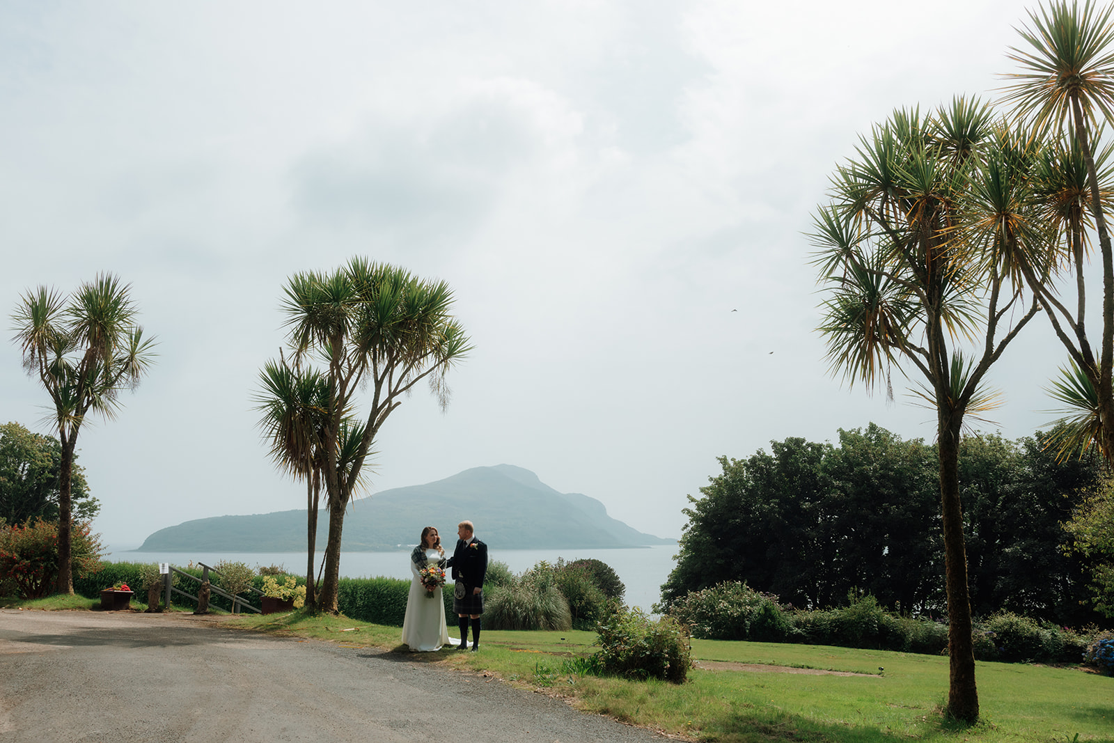 Elopement couple standing beneath palm trees on the Isle of Arran.