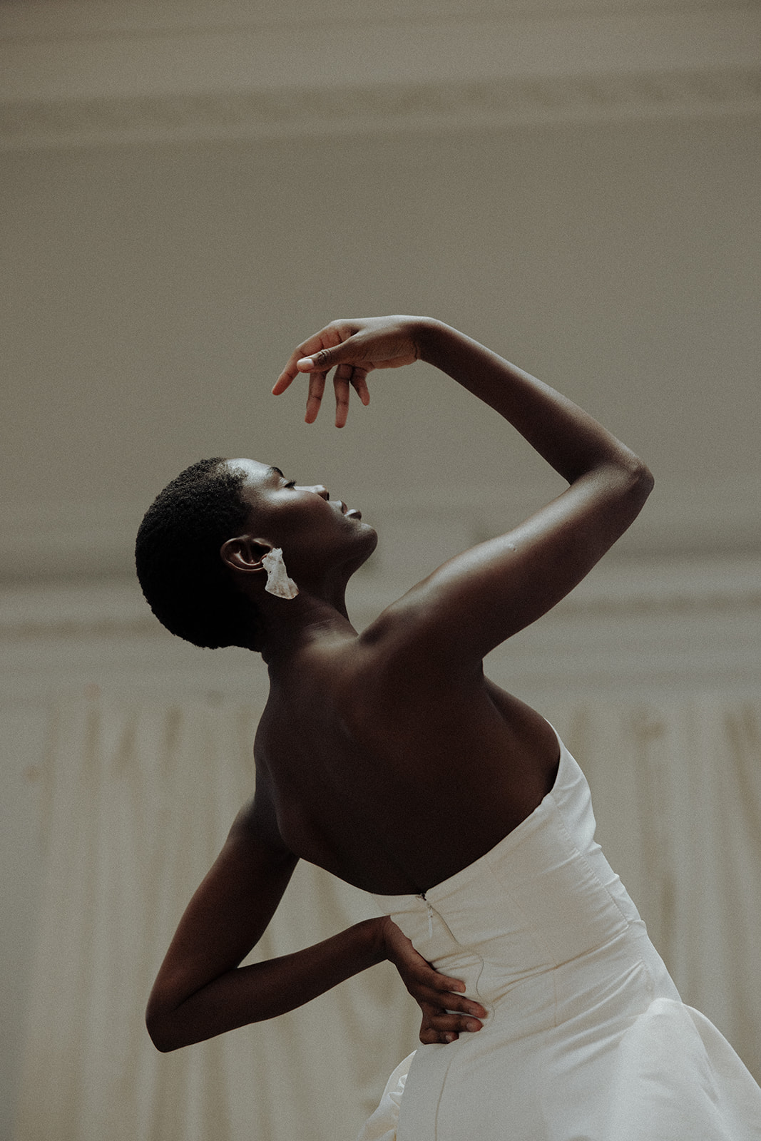 Bride in strapless couture gown with arm raised, modern editorial bridal photograph.