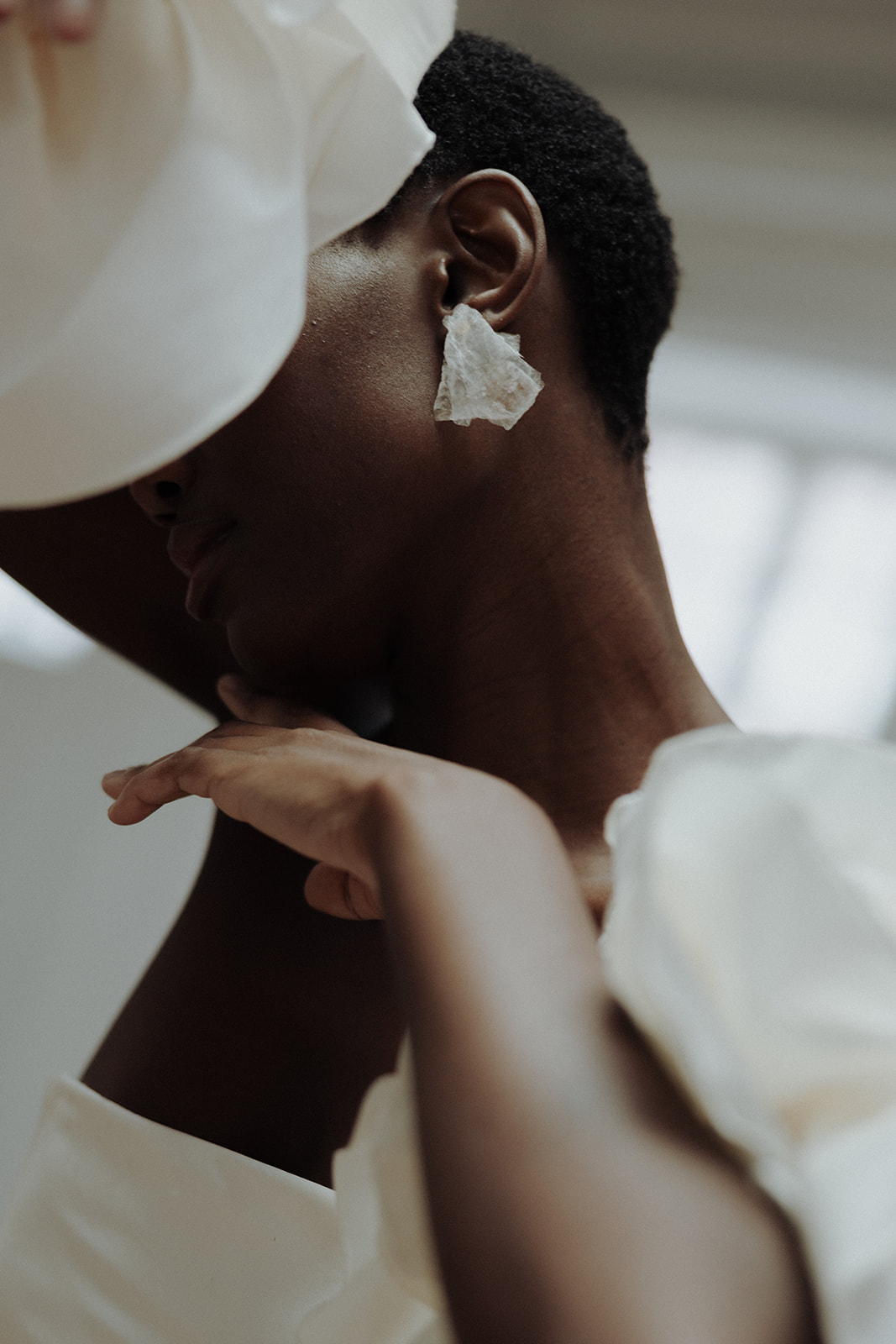 Close-up detail of bride wearing floral earrings beneath veil, editorial bridal portrait.