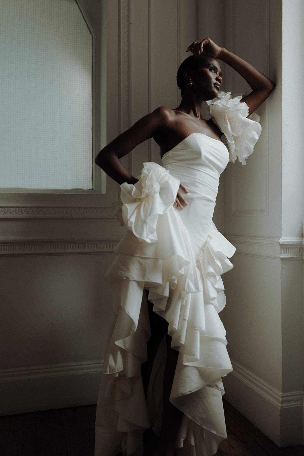 Bride in couture gown wearing sculptural floral earring, close-up editorial portrait.