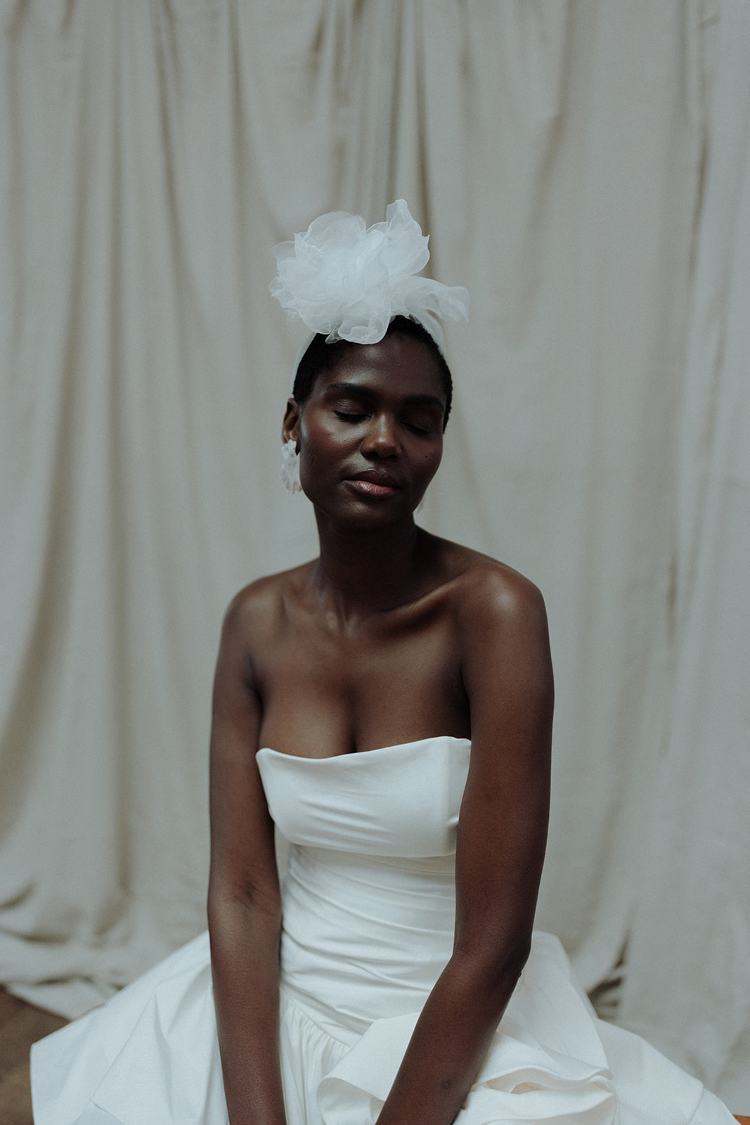 Bride wearing Darla Haute Couture gown and tulle headpiece, seated editorial bridal portrait.