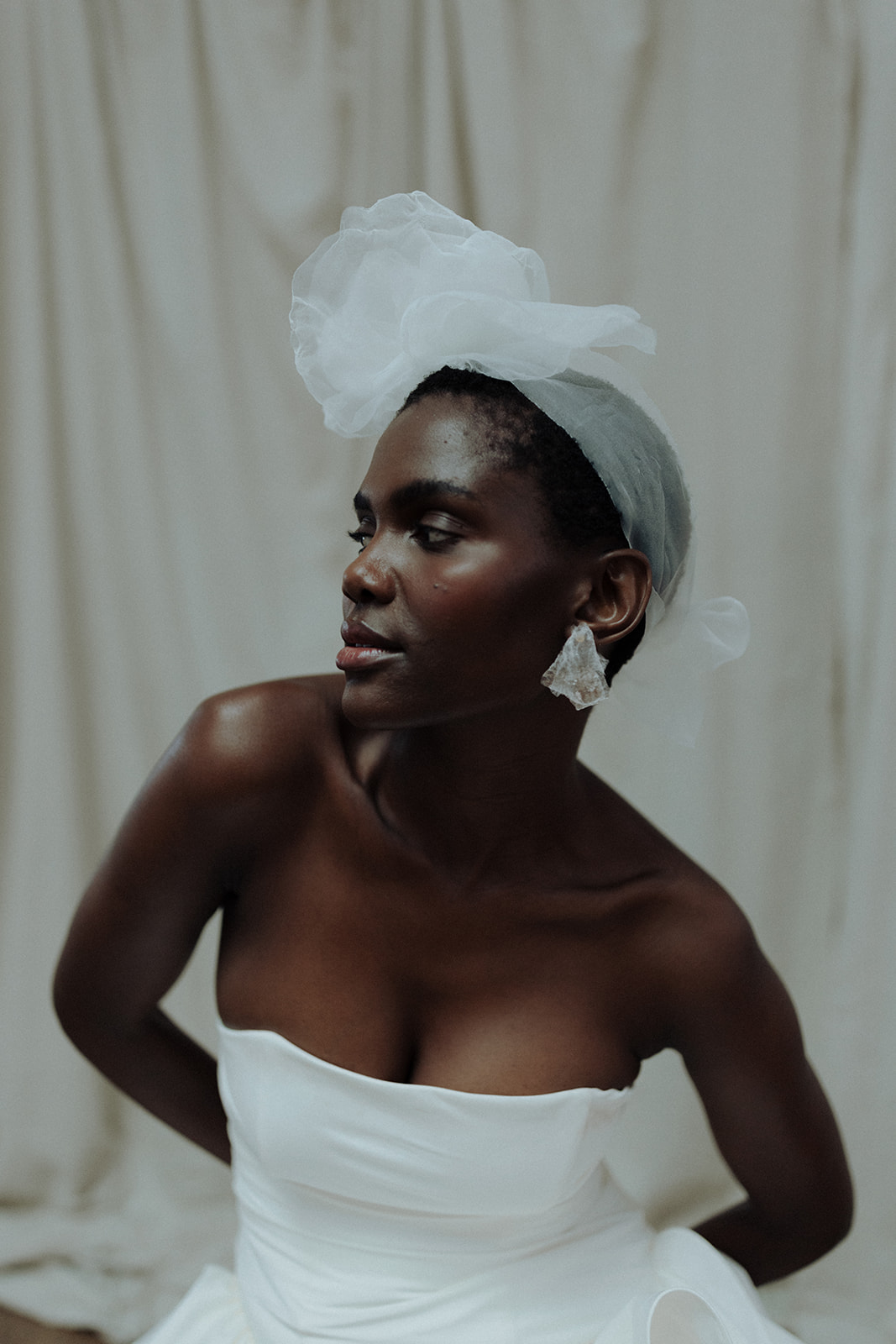 Bride in couture gown with tulle headpiece, modern editorial bridal portrait.