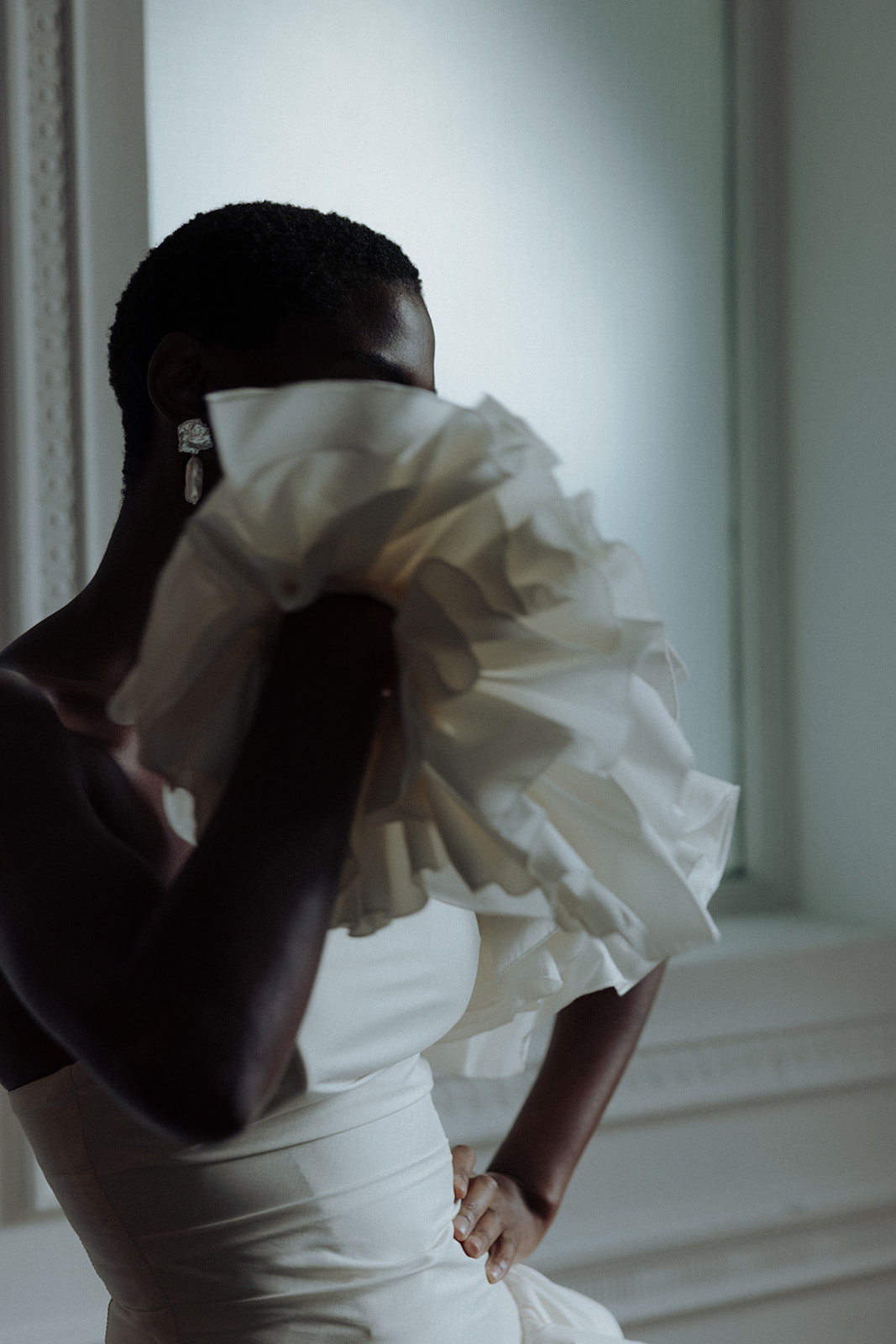 Bride holding ruffled Darla Haute Couture gown, modern editorial bridal photograph.