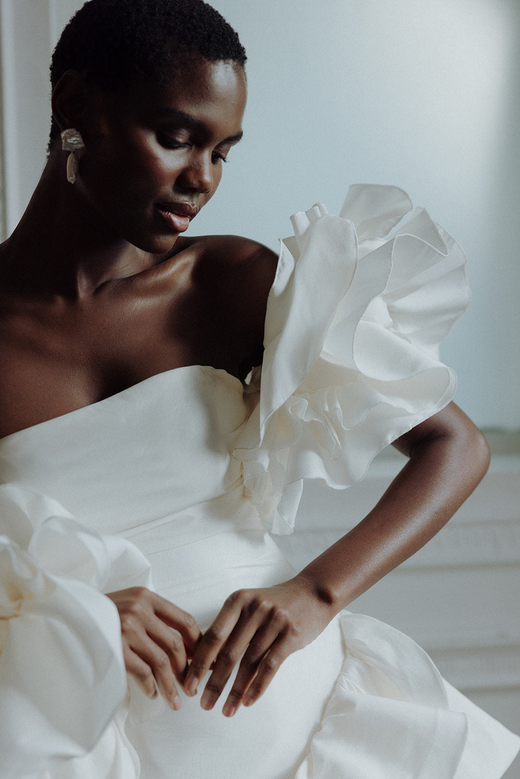 Bride in asymmetric Darla Haute Couture gown, dramatic light and shadow editorial portrait.