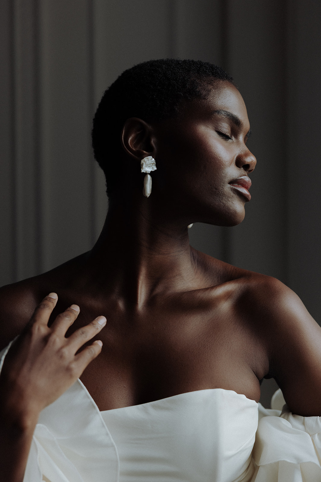 Bride in sculptural off-shoulder Darla Haute Couture gown wearing luminous Lori Muldoon statement earrings, editorial wedding portrait.