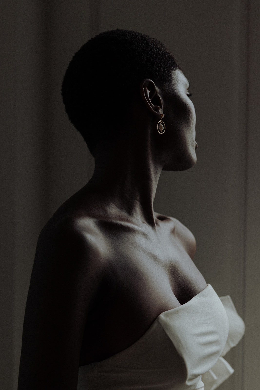 Bride in couture gown at window, editorial bridal portrait.