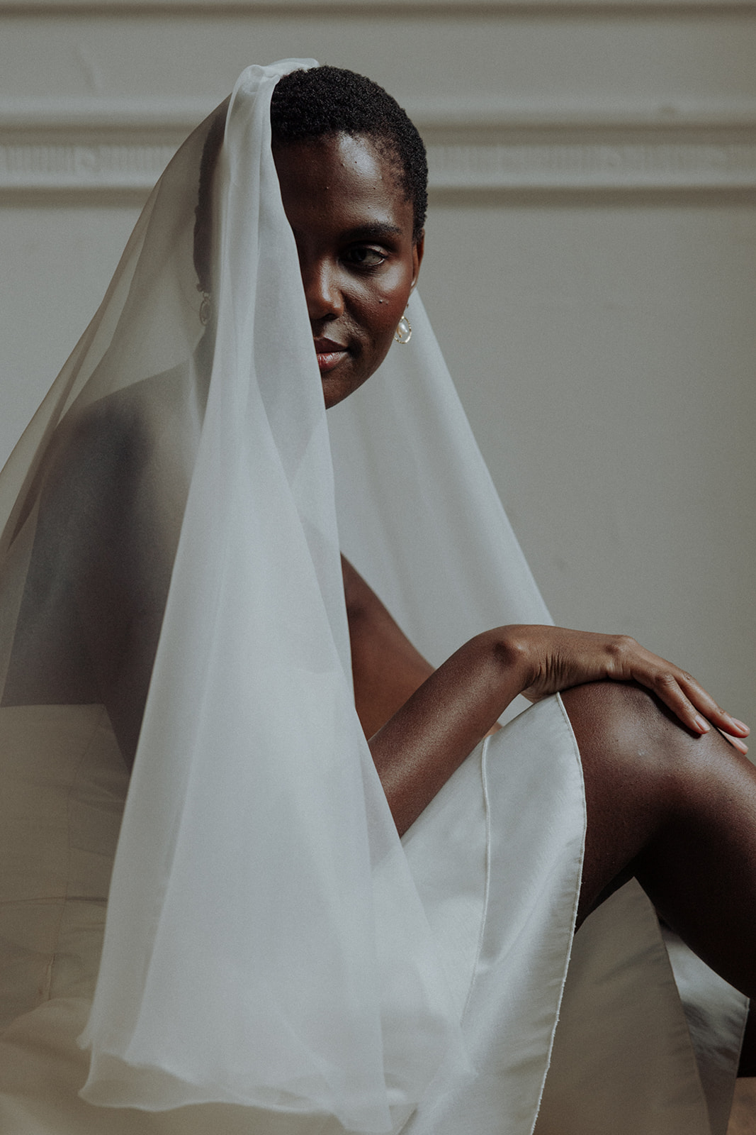 Bride in couture gown with dramatic ruffled sleeve, close-up editorial bridal photograph.