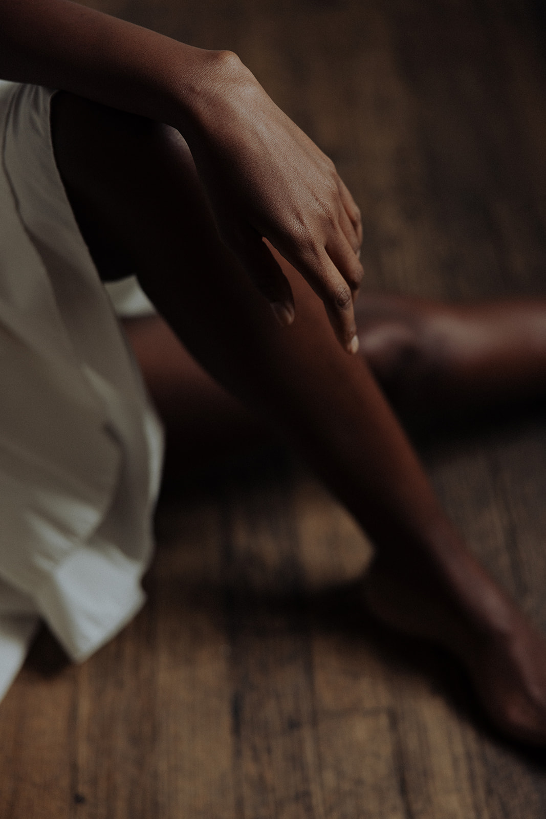 Detail of bride’s legs and couture gown against wooden floor, editorial bridal photograph.